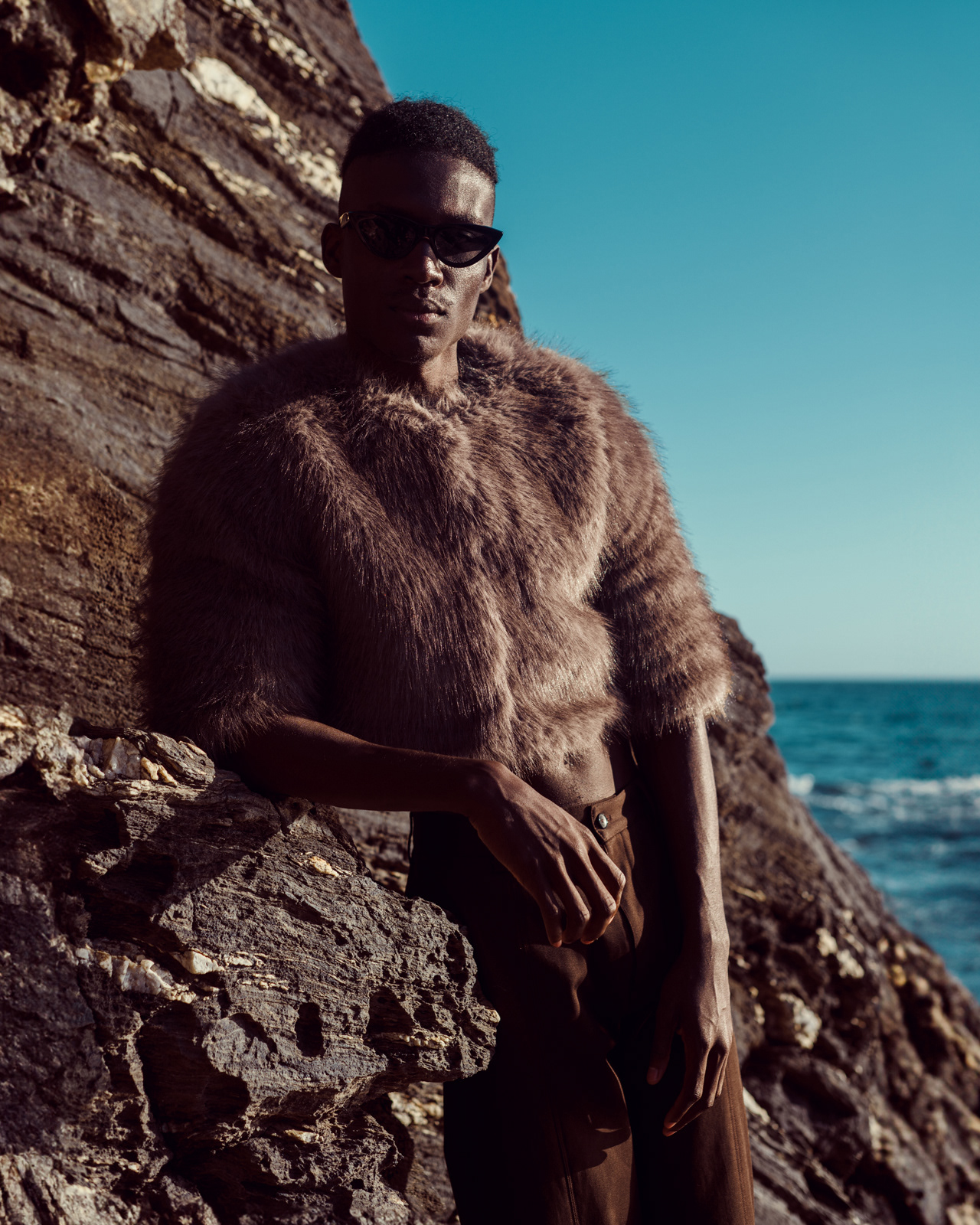 Men’s fashion portrait with brown fur sweater and sunglasses by rocky beach – Joanna Kustra commercial fashion photography