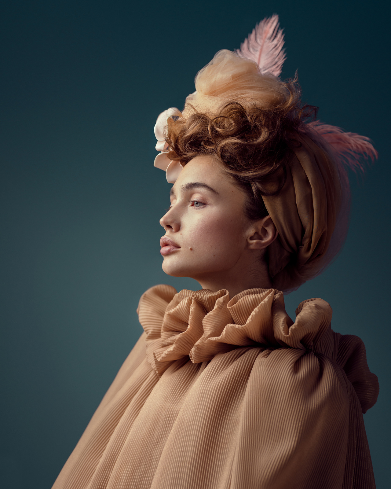 Profile beauty portrait with feather headpiece and beige pleated gown – Joanna Kustra creative fashion photography