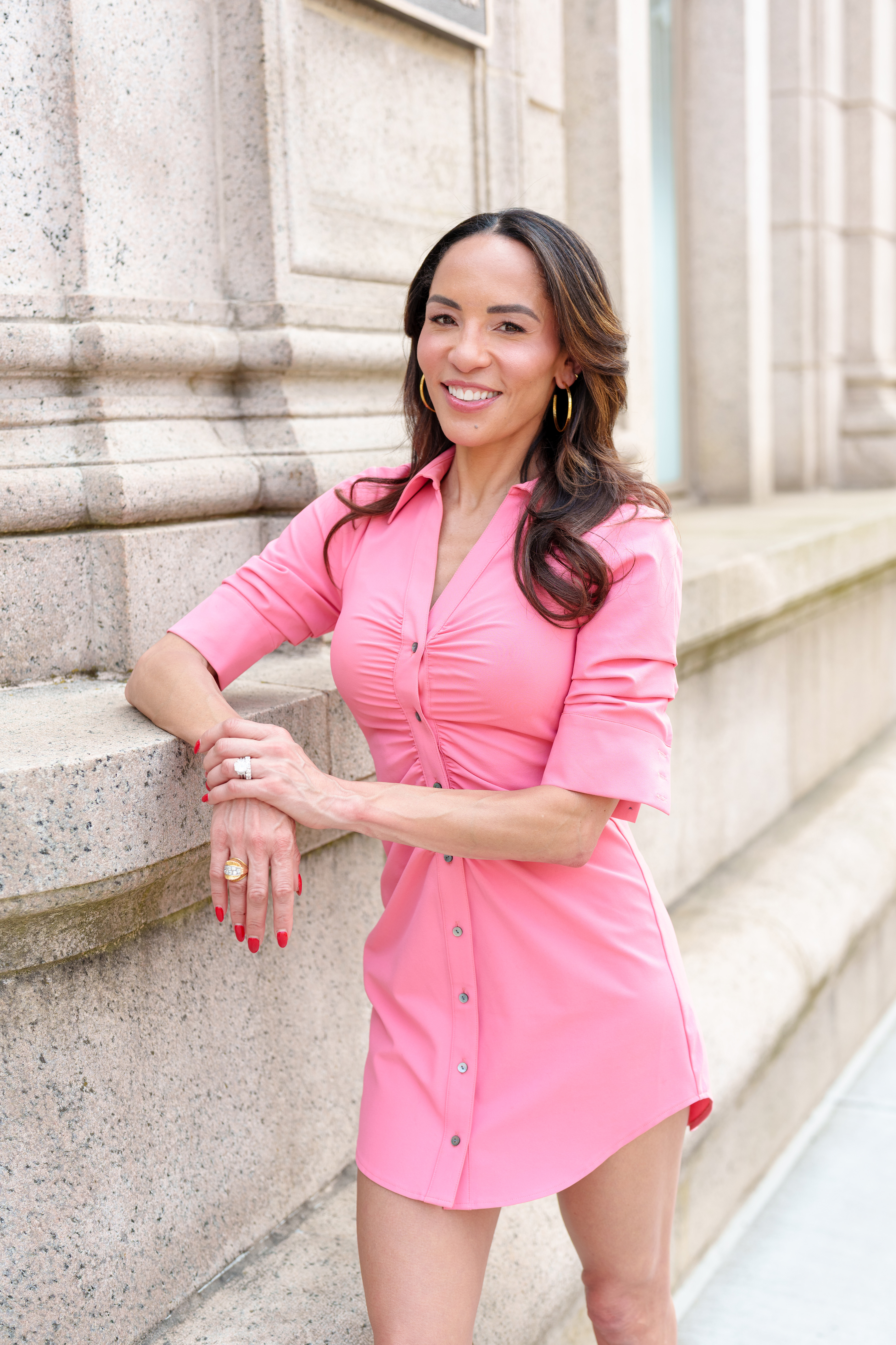 Dr. Kim Nichols posed against a building on Greenwich Ave, wearing a 3/4 sleeve pink button down dress