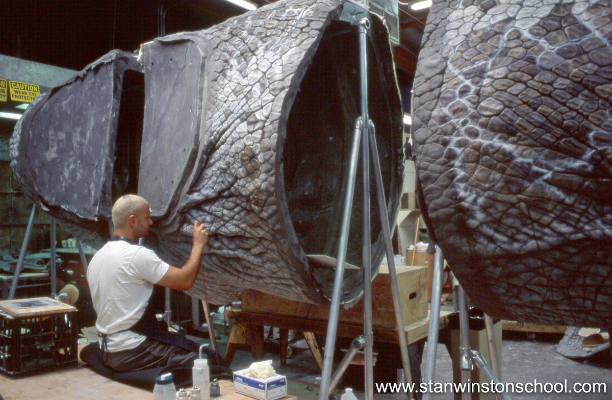 Painting details onto the skins of the gigantic Spinosaurus puppet.