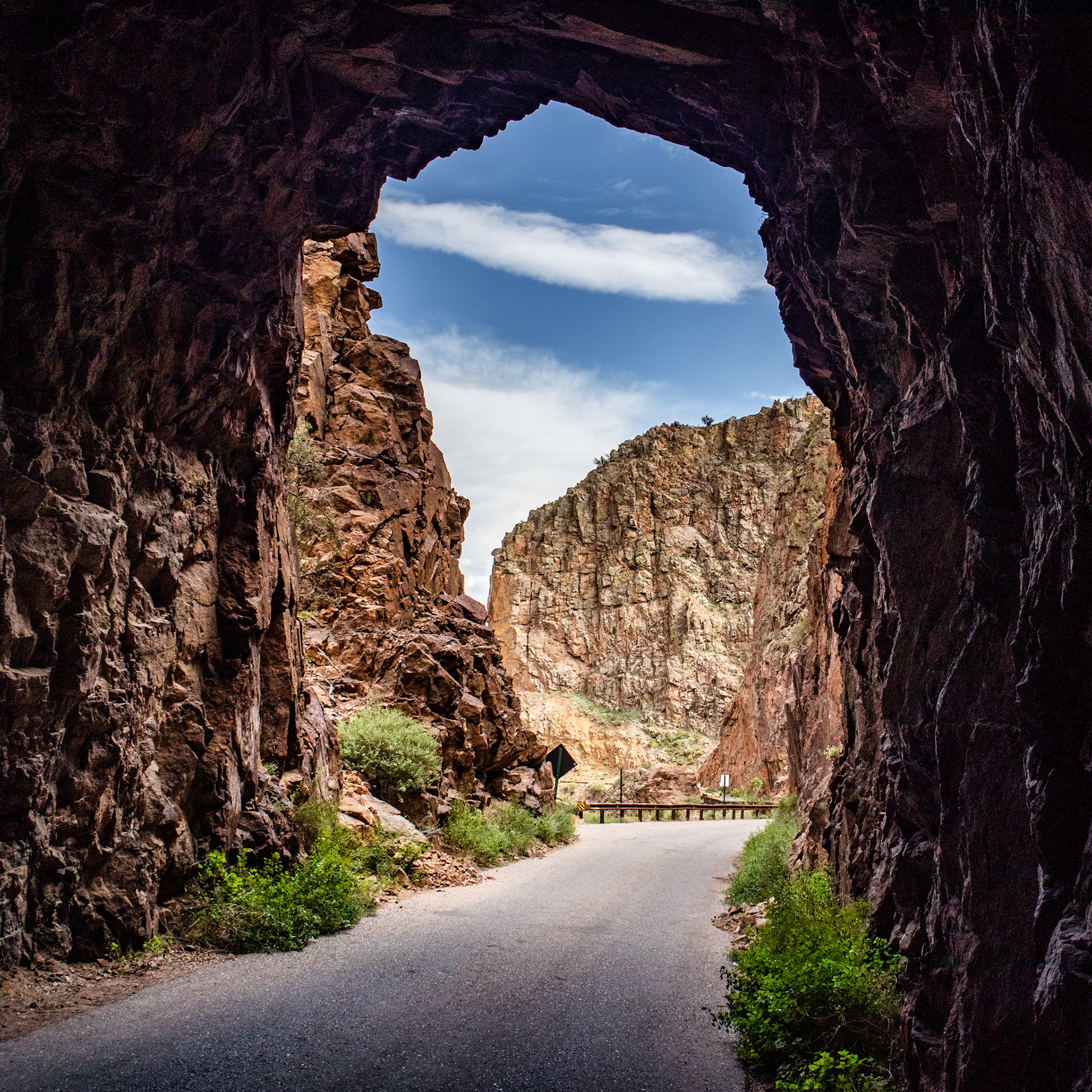 The Gilman Tunnels were a part of the former Santa Fe Northwestern Railway, which operated a logging route in the Jemez Mountains 1924-1941. Logging operations continued by truck until 1973. The land is now part of the Santa Fe National Forest. The stone it passes through has been radiometrically dated to 1.45 billion years old - a Precambrian monzogranite. The tunnels sit almost exactly on the Jemez-San Ysidro fault line, and you can see the slip just after the second tunnel.