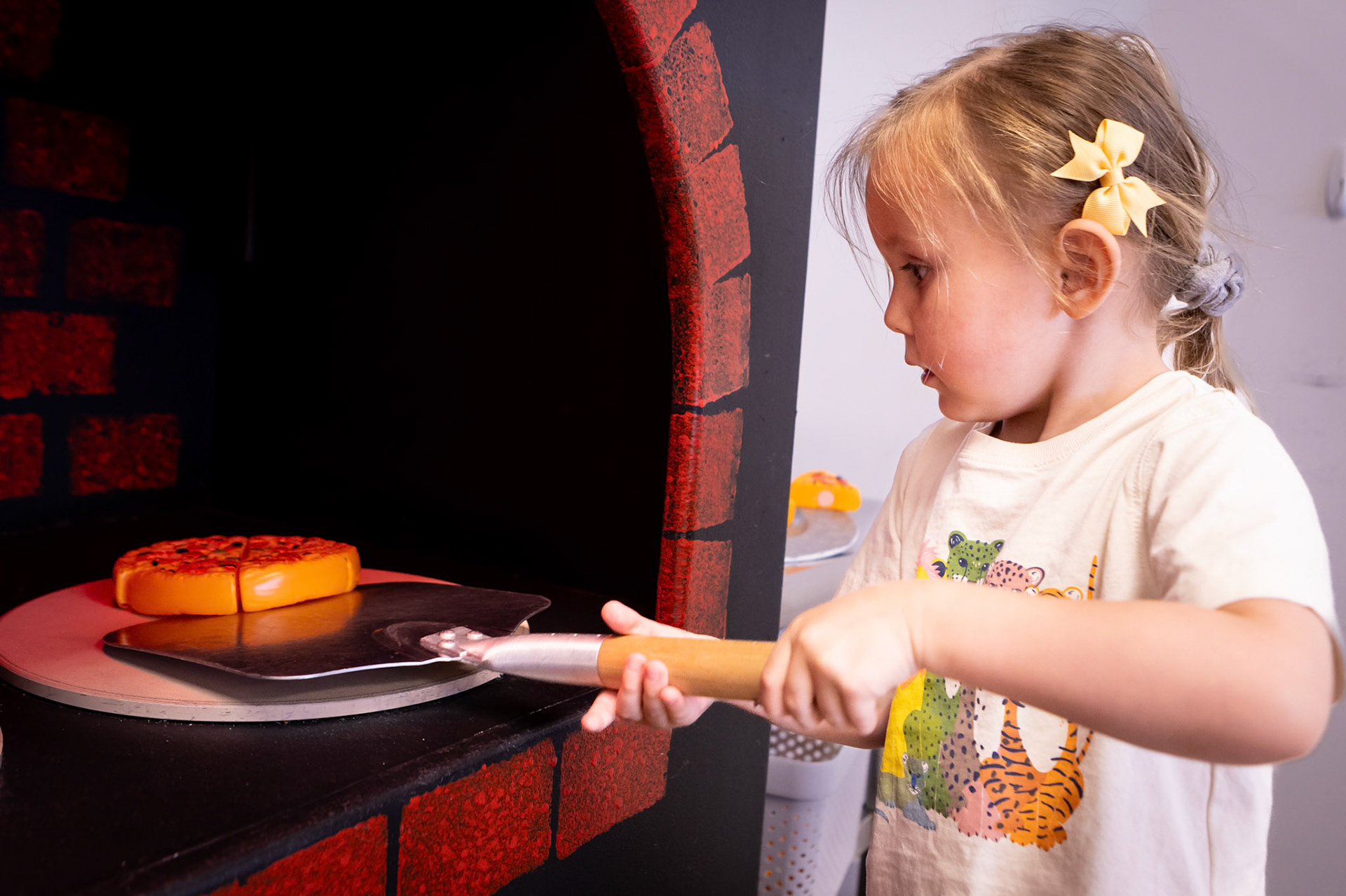 Spinning a pie in the pizza oven at Kid's Wonder