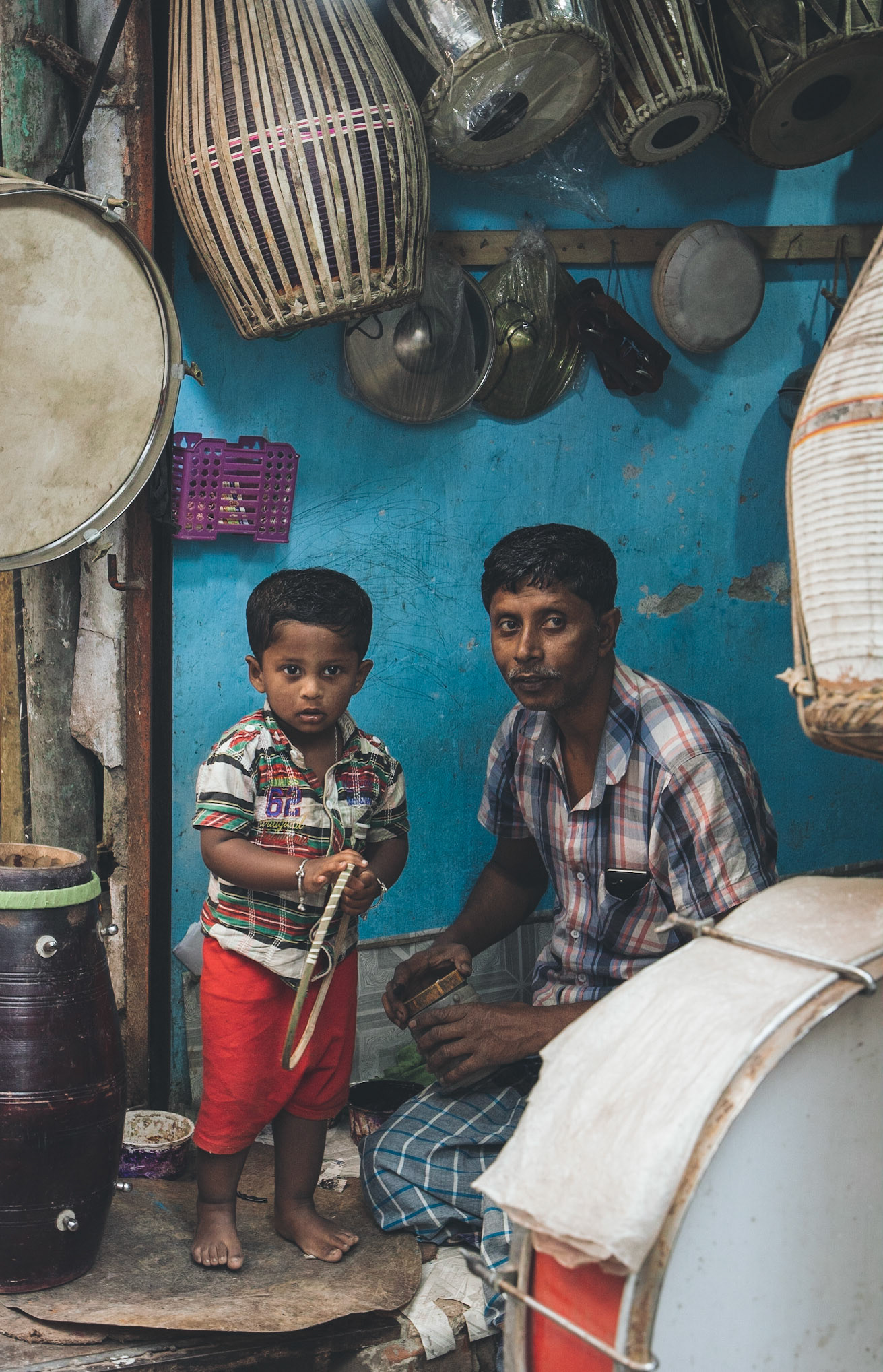 A young child helping his father make drums, Hindu Street, Old Dhaka, Bangladesh.