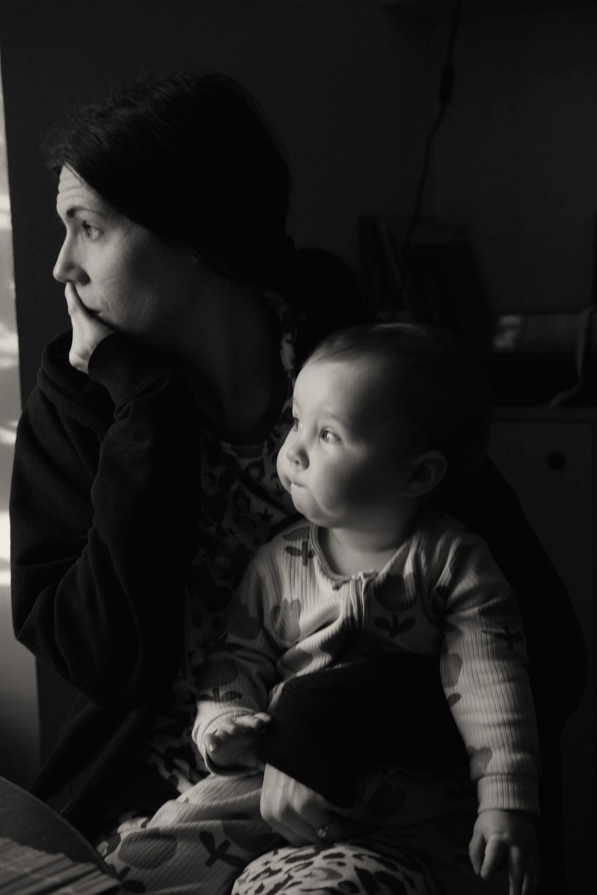 Woman with a baby look out of a window