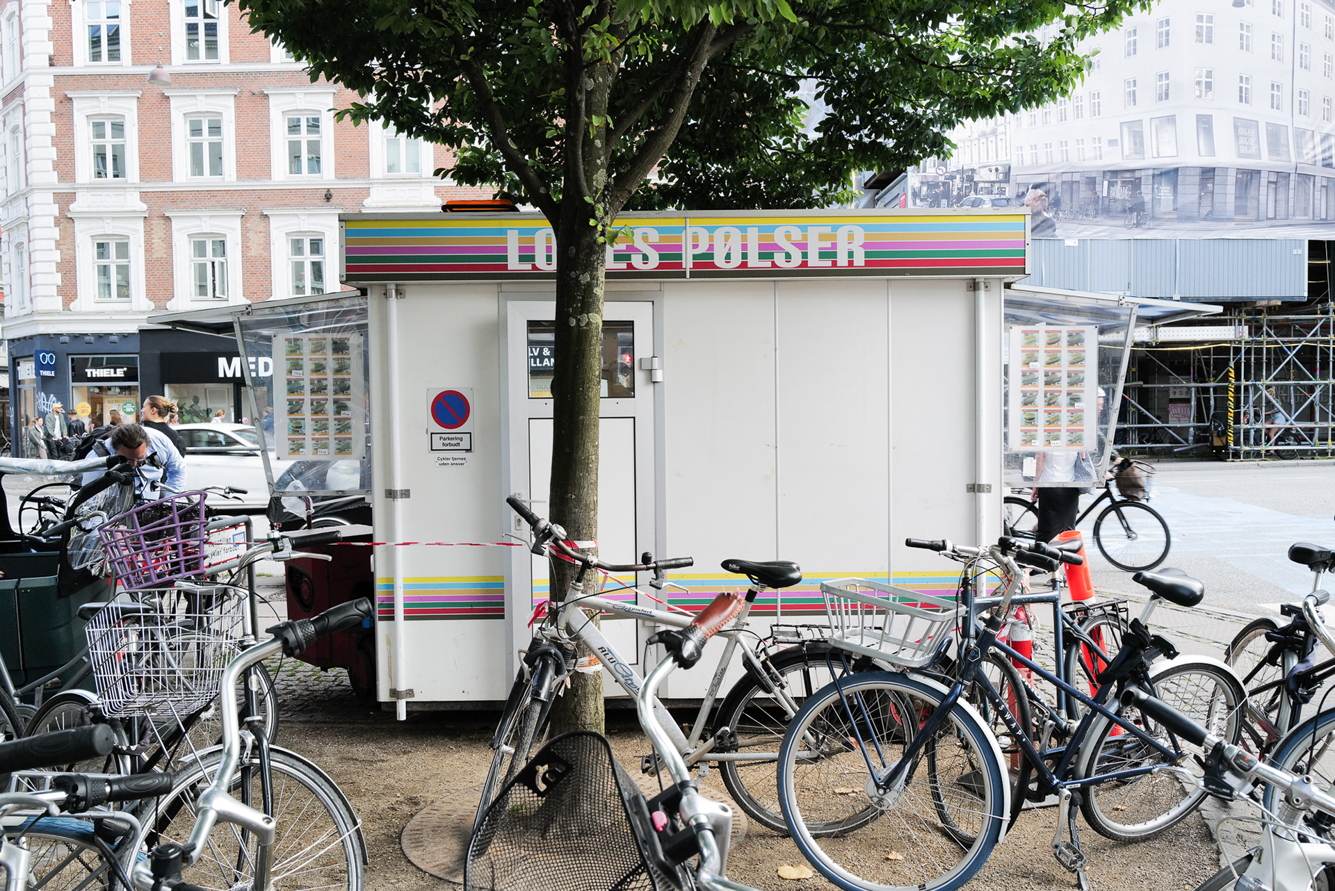 Un stand de hotdog à Copenhague. Le stand aux couleurs bariolées est entouré de vélos.