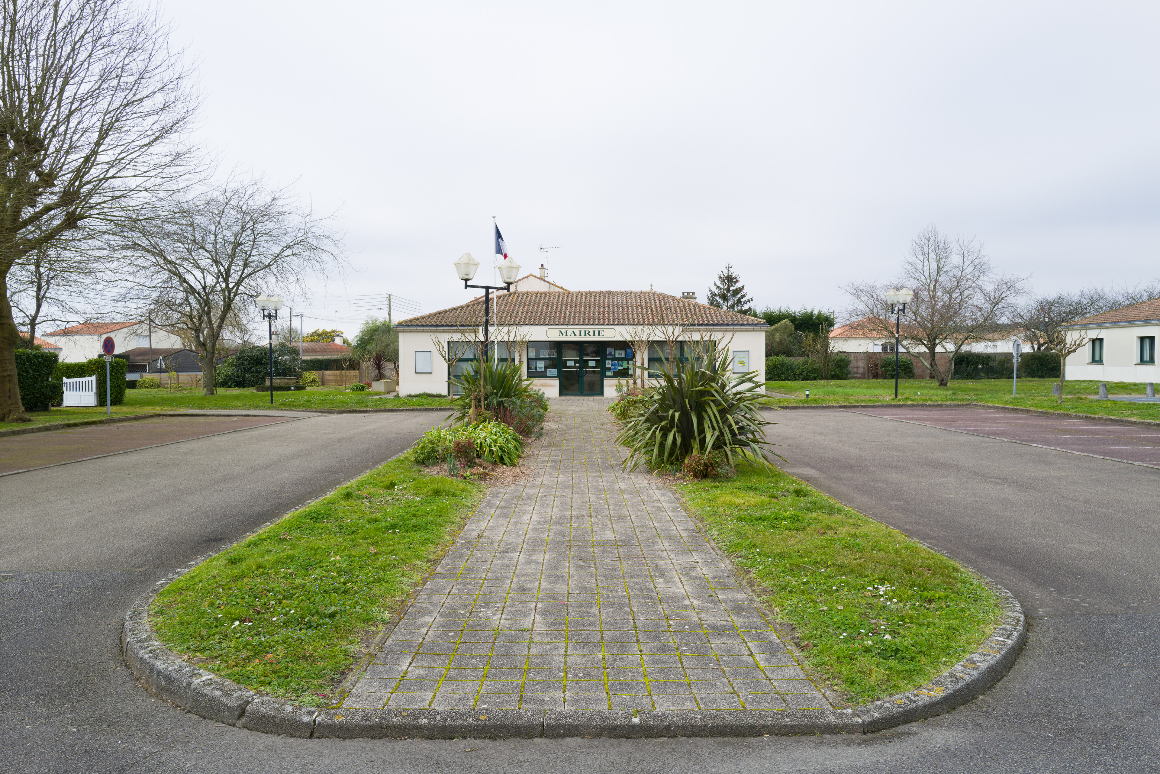 Mairie au bout d'une allée pavée entourée de places de paring vides