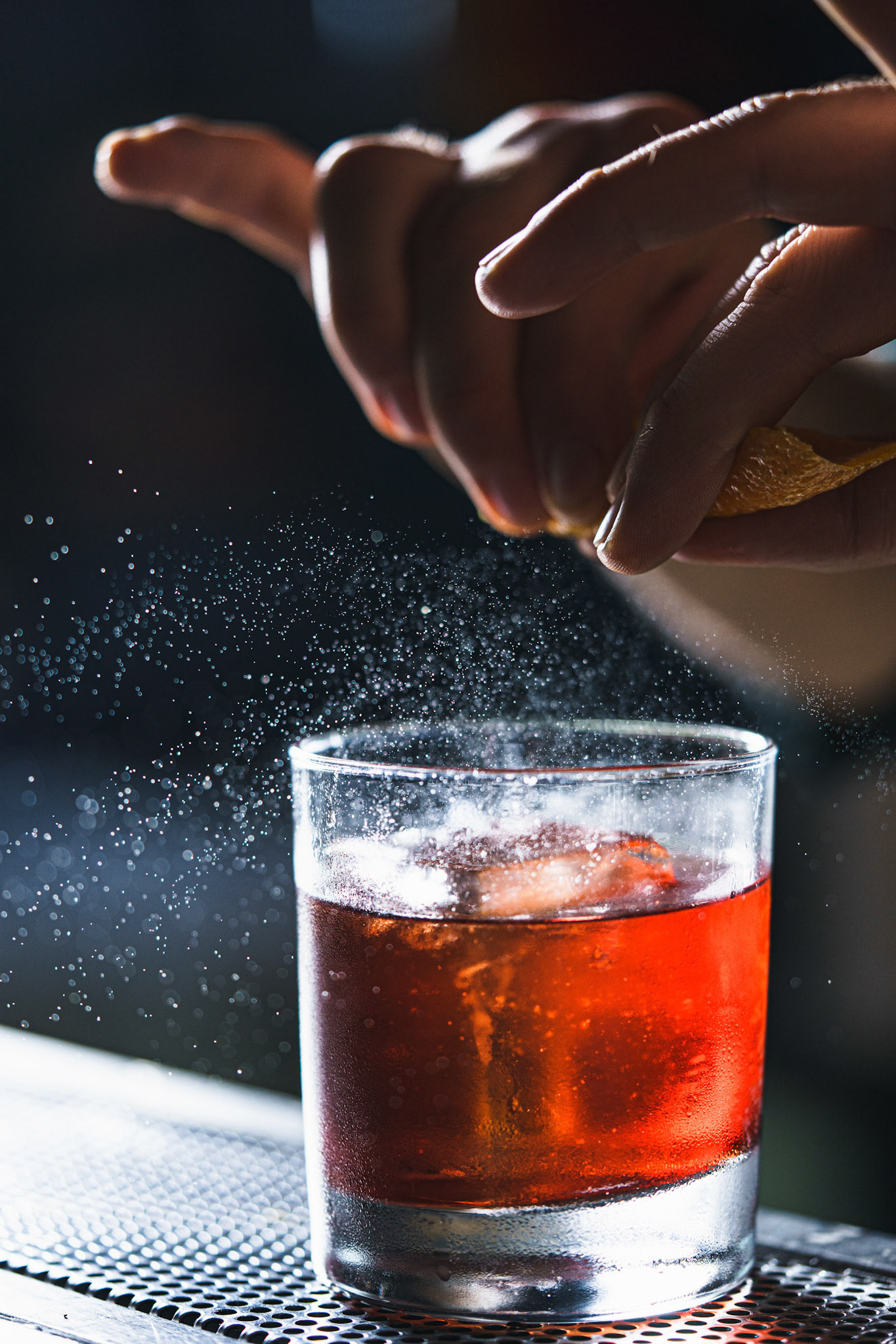 Gotas de aceite natural de naranja cayendo en un negroni