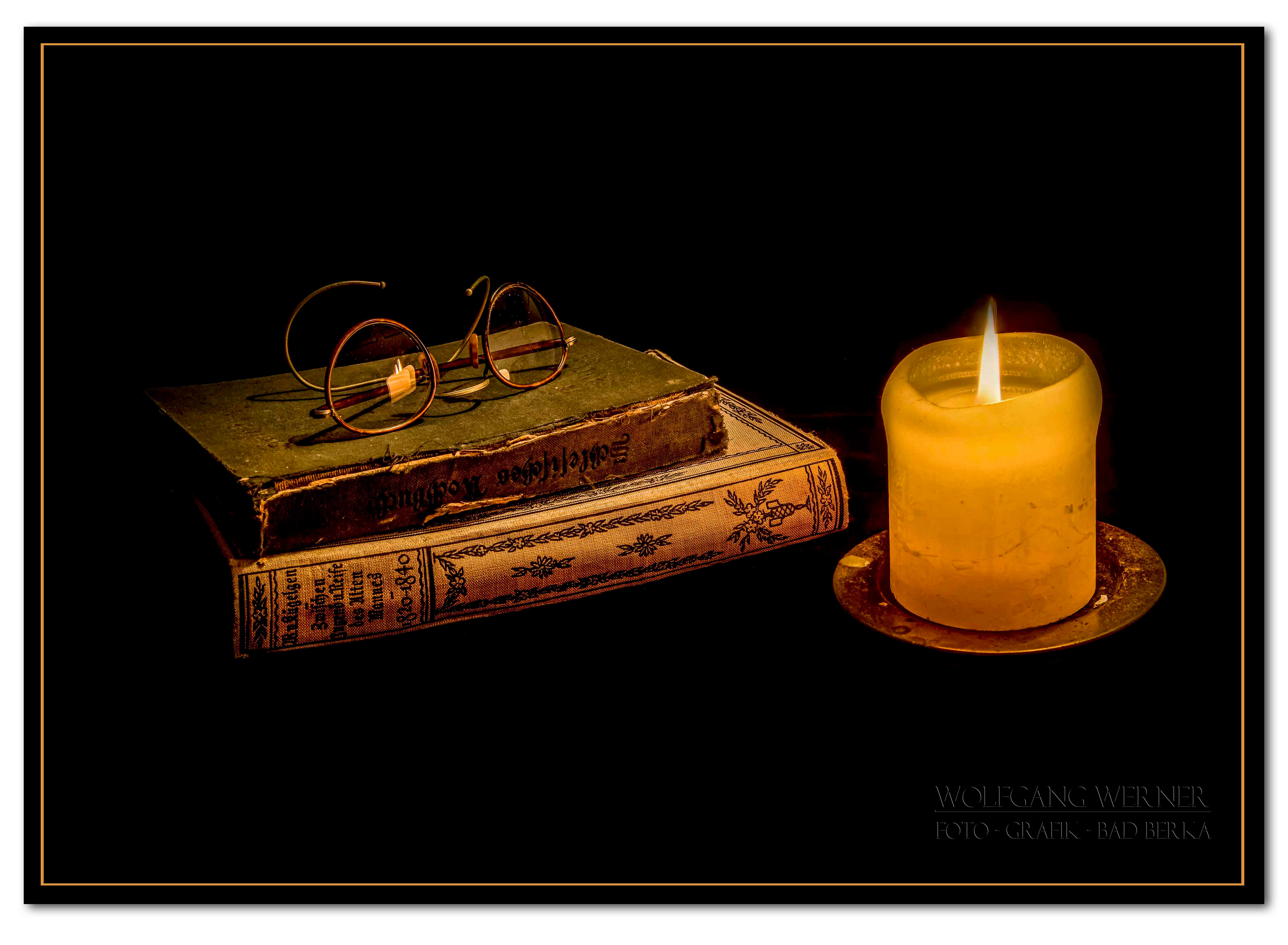 Stillleben mit Büchern und Kerze auf schwarzem Grund