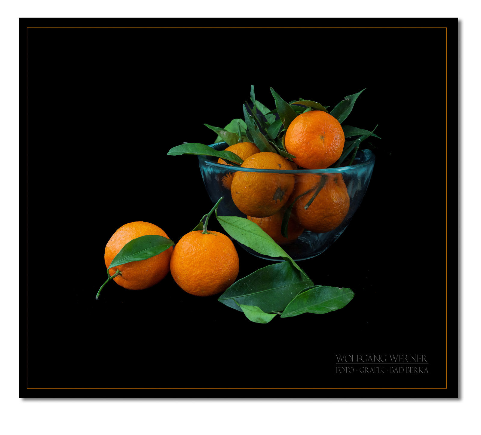 Glasschale mit Mandarinen auf schwarzem Grund