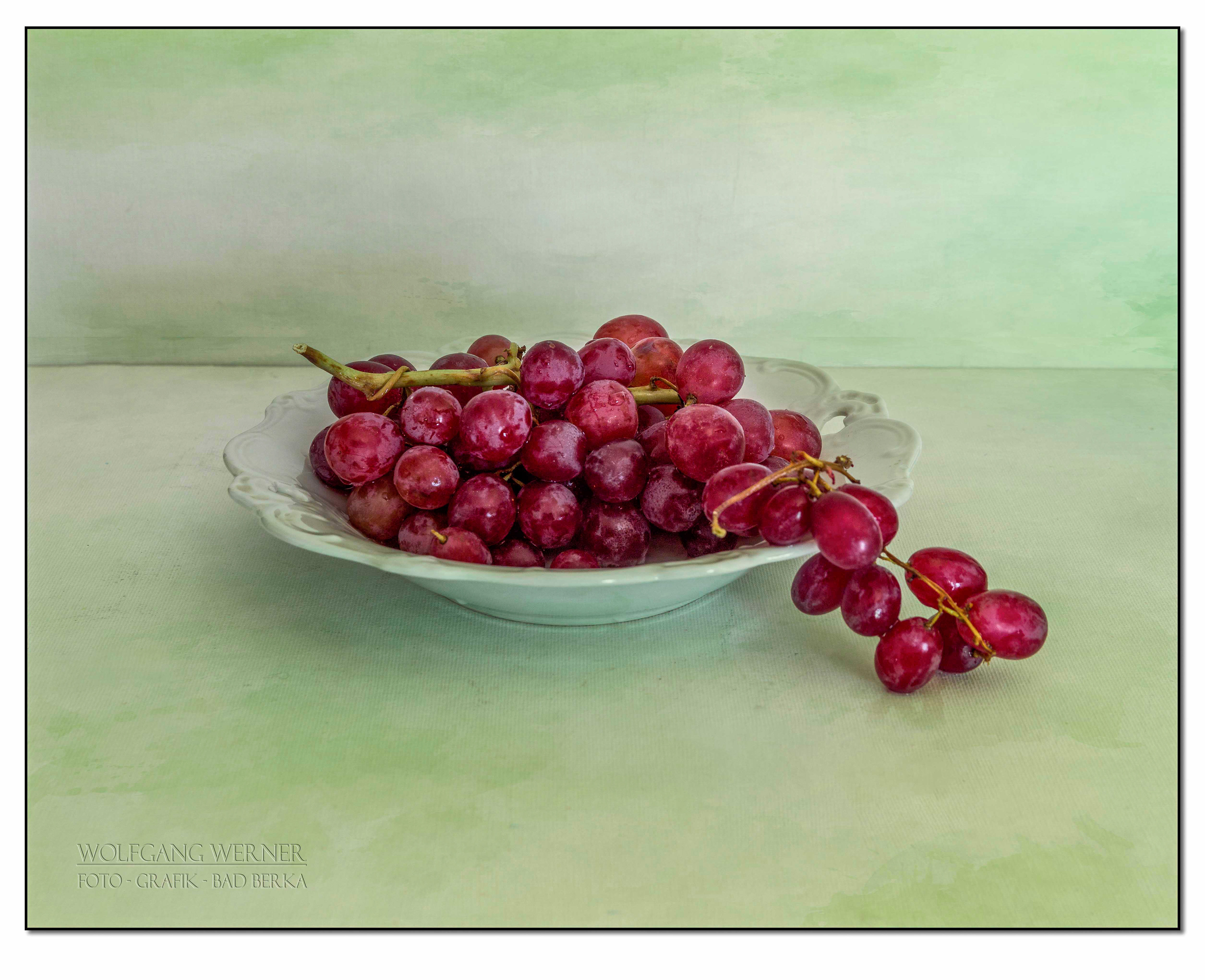Schale mit Weintrauben auf farbigem Grund