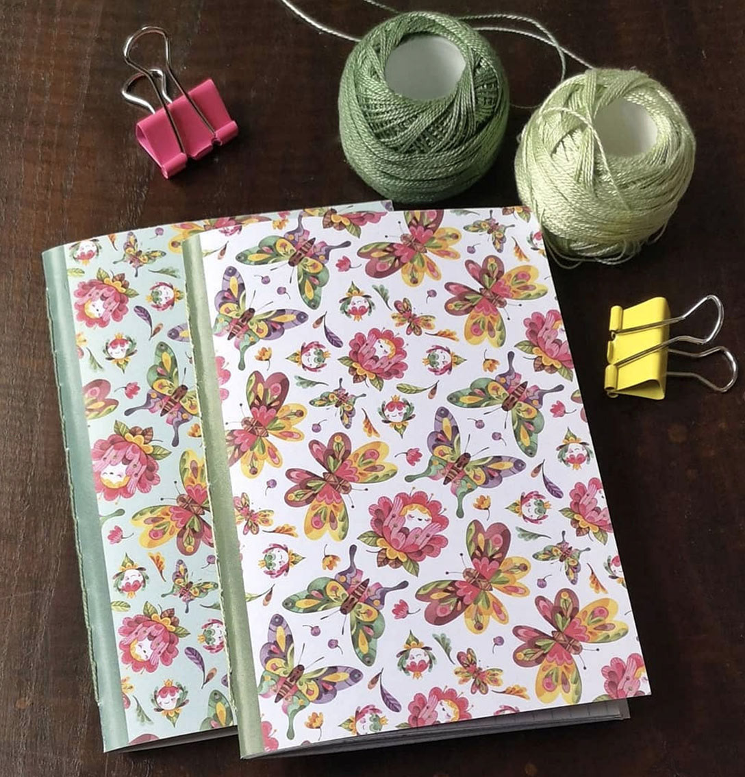 Photo of two hand stitched notebooks. The cover features a butterfly pattern that designed by Gaia Bordicchia
