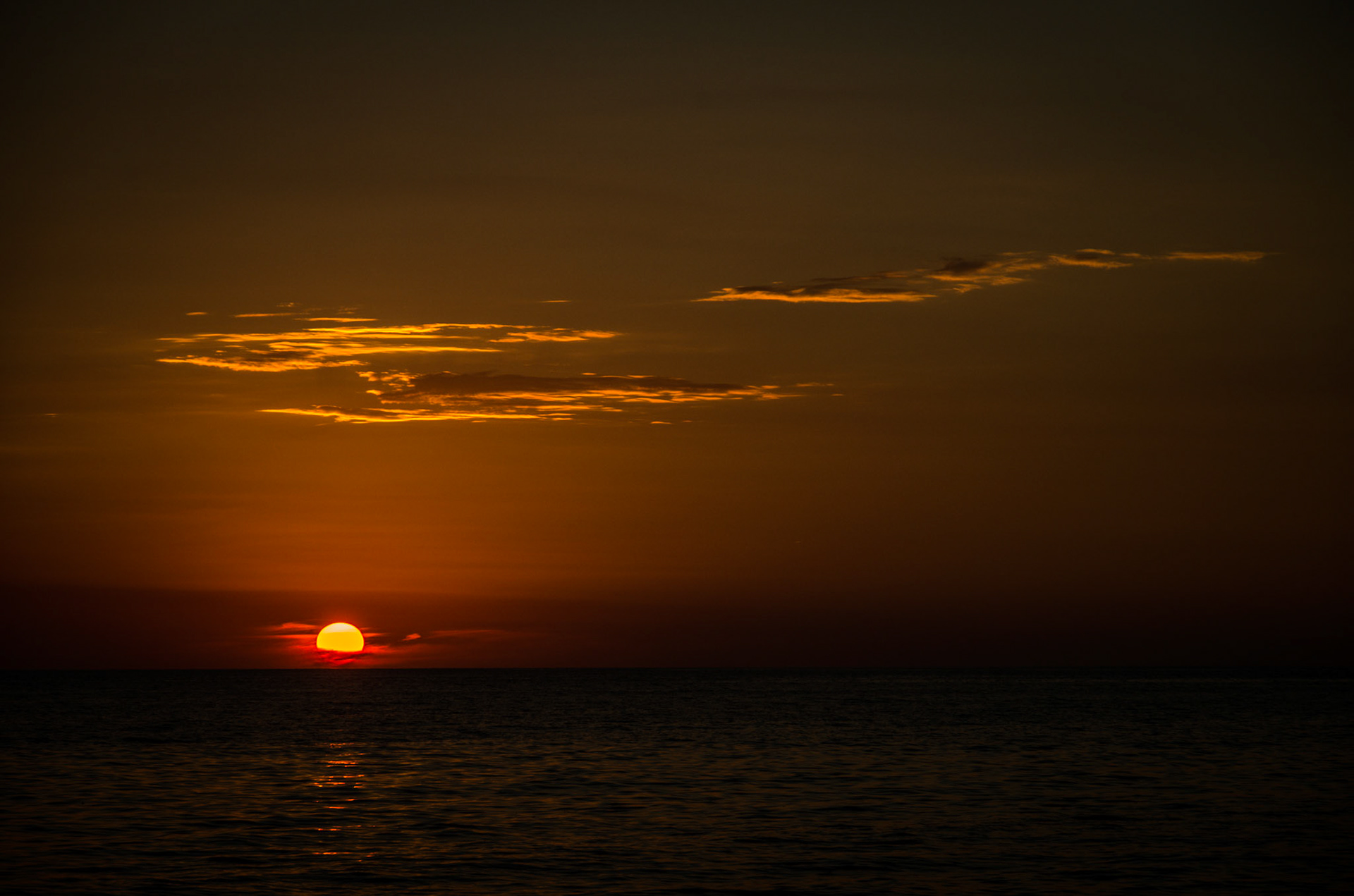 Wien ein glühender Feuerball liegt die Sonne am Horizont kurz bevor sie im Meer verschwindet.