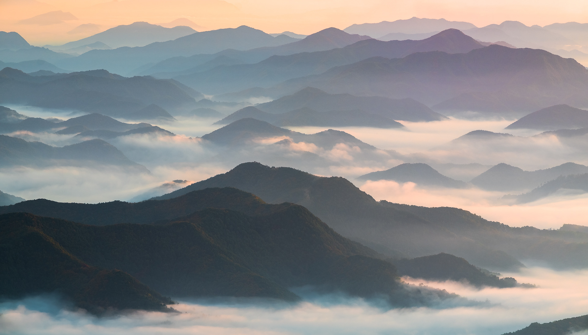 Early Morning sunlight lighting up layers of mountain ridge and fog. 