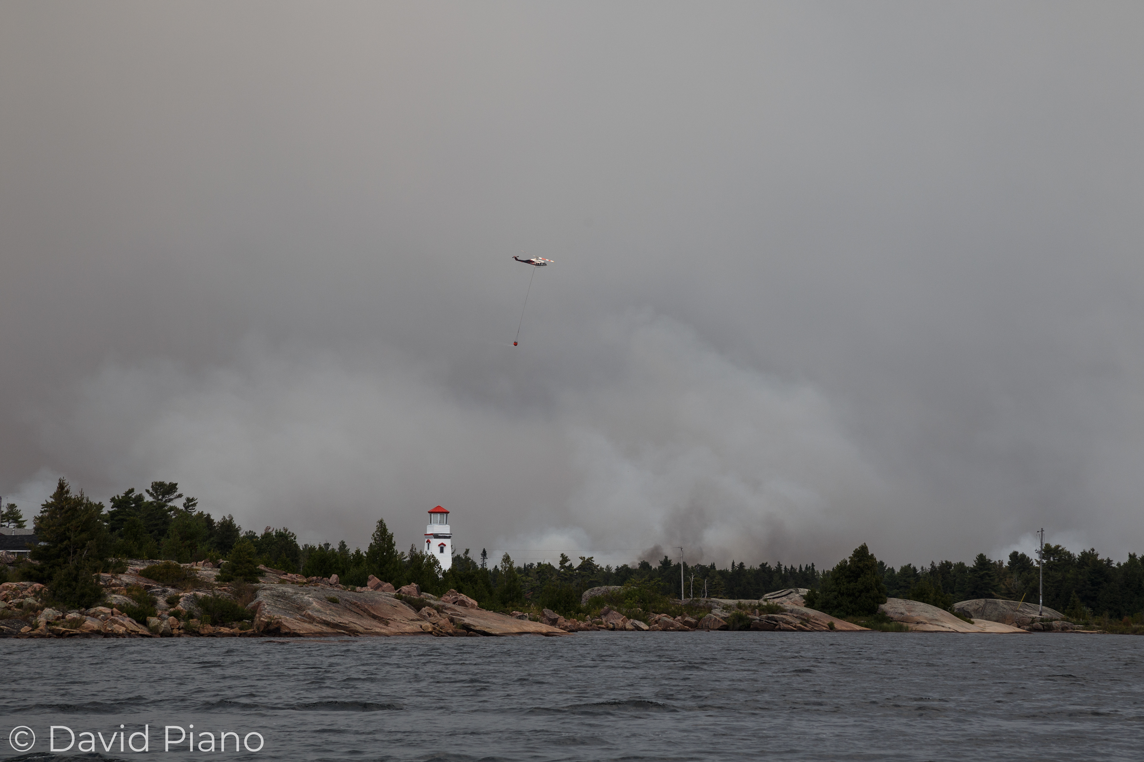 Bucketing helicopter drops water behind the Key Harbour Lighthouse - Parry Sound 33 Forest Fire - 07/21/2018