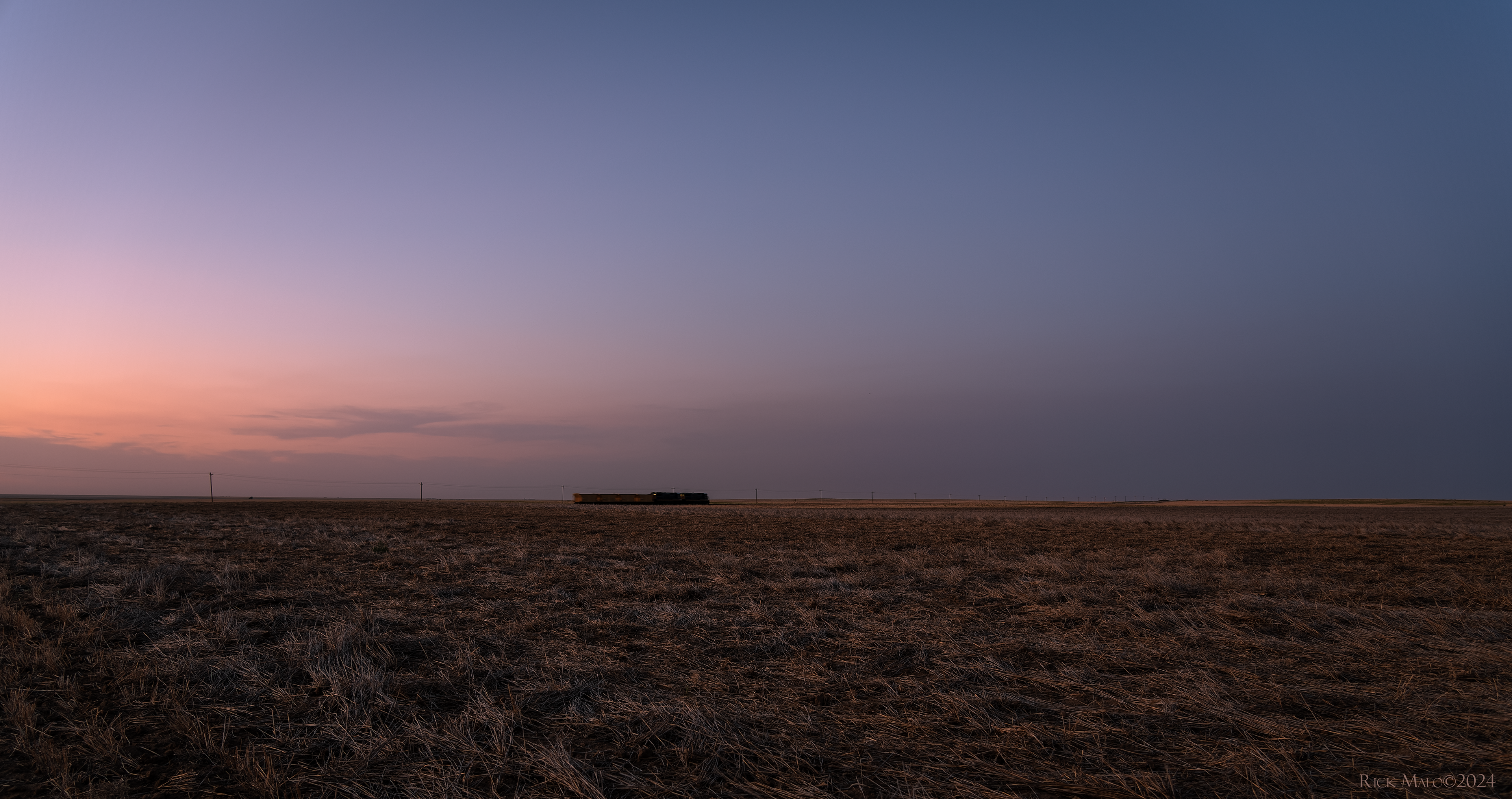 A June 2020 dusk settles over southwestern Kansas as a short train rolls east on the Cimarron Valley Railroad's former ATSF Manter Branch.