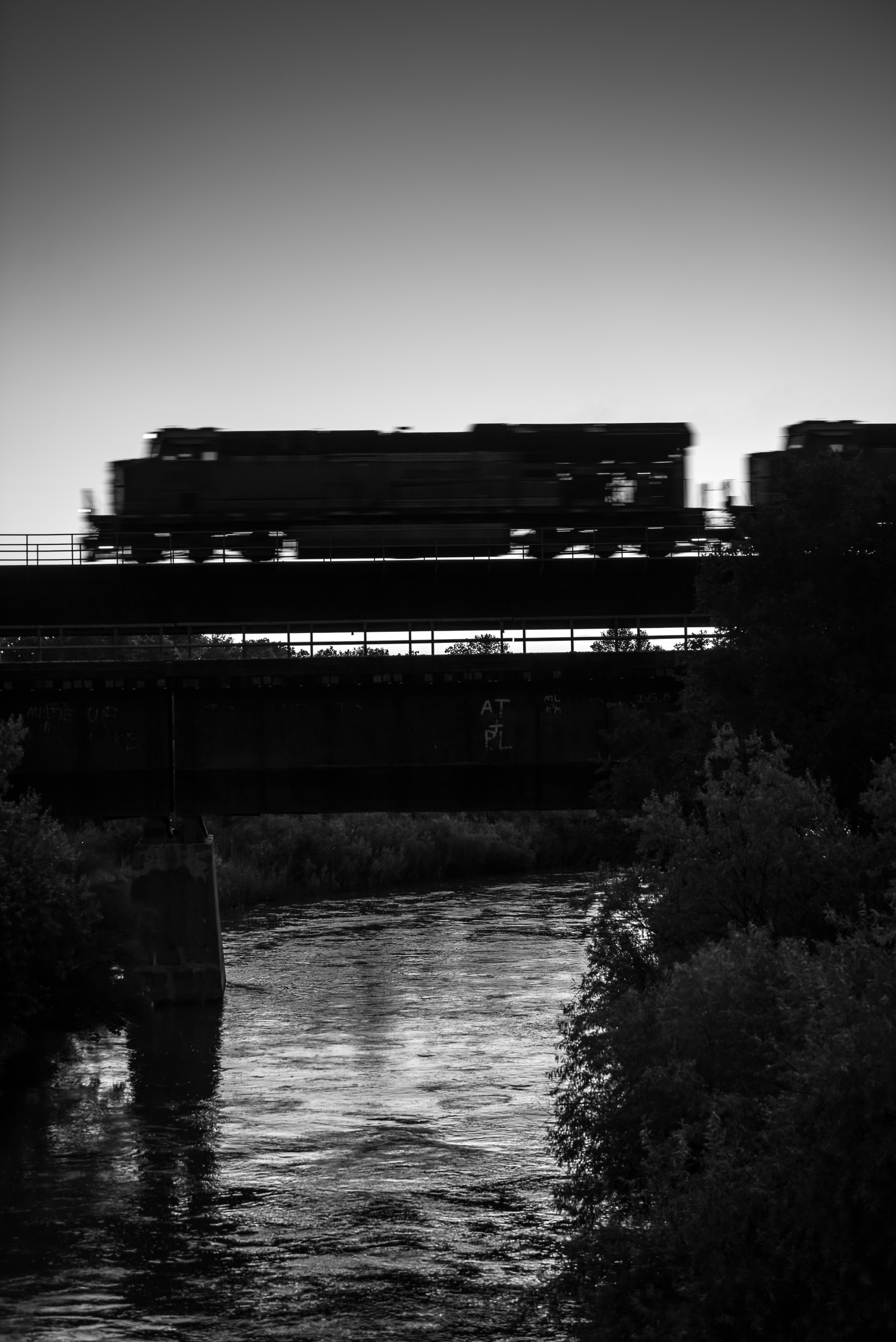 On a summer dusk, a fast BNSF train rolls westbound over the Canadian River at Canadian, Texas.
