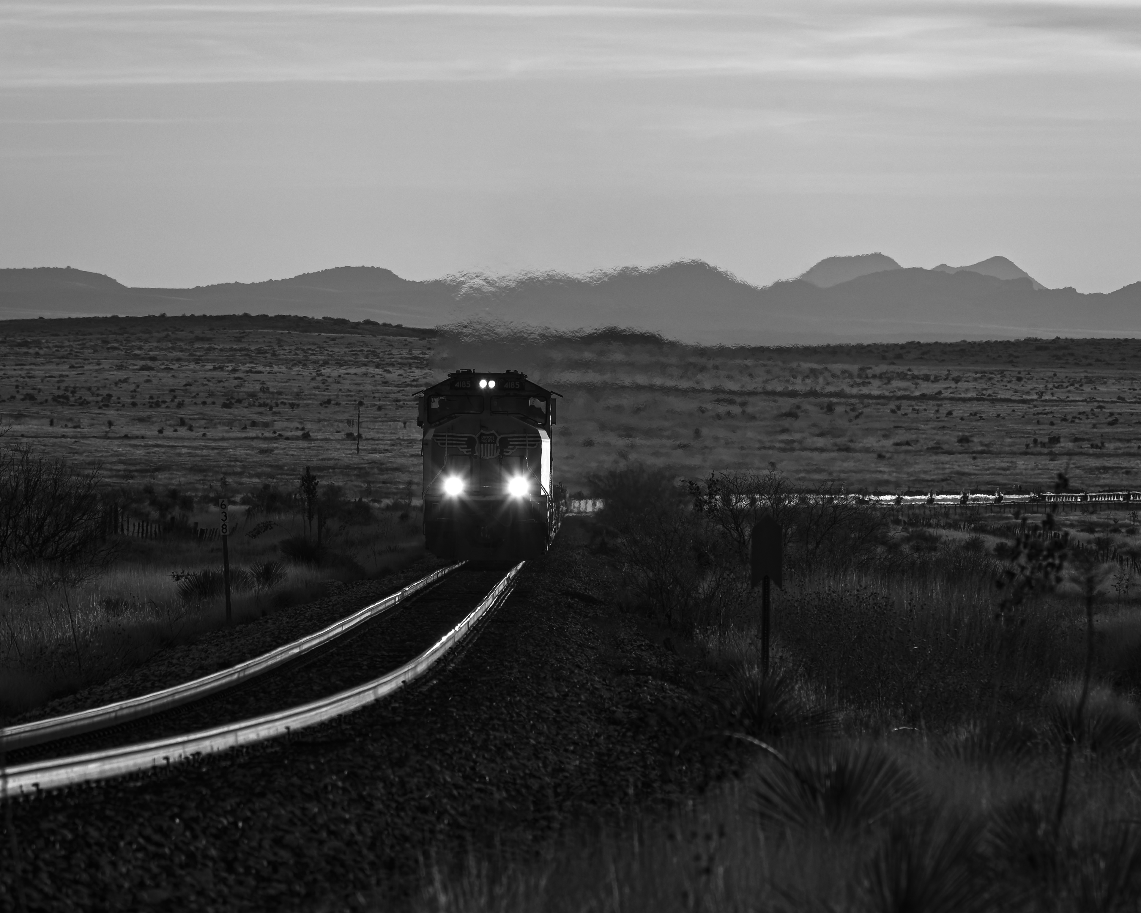 West of Marfa, Texas on a cold December 2021 morning, a lone SD70M rolls a string of empty well cars west along the Sunset Route as the mountains of Twin Sisters and the Paisano caldera rise in the background.