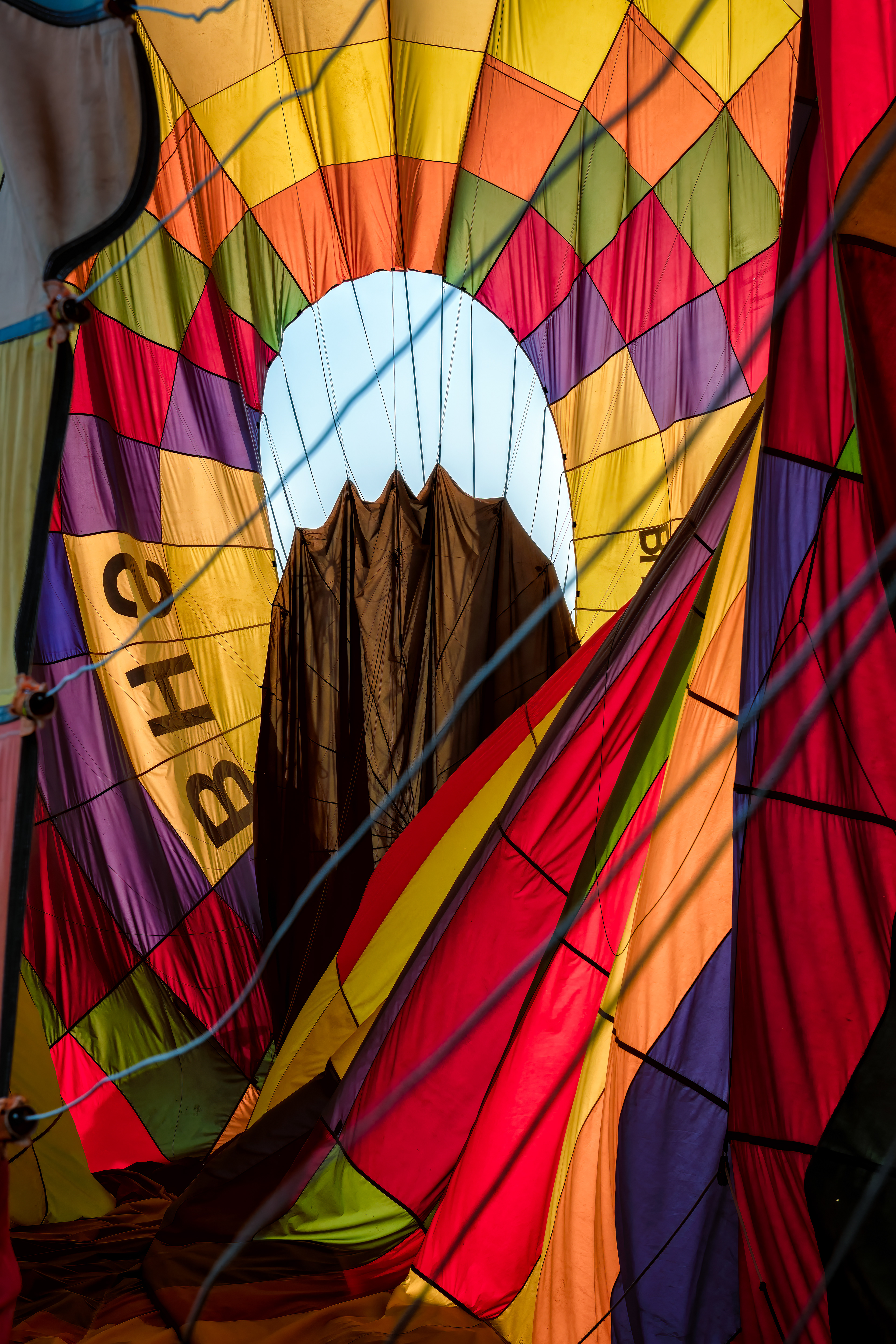Looking straight up into a balloon's canopy — the pattern radiating outward is gores, individual fabric panels of nylon and polyester, cut and sewn together (diagonal cuts waste the least material, which is why most balloons use them) into a shape that holds air rather than water. An envelope like this is good for roughly 400 hours of flying before it's retired. The basket underneath, meanwhile, is still just rattan and willow woven together, the same material it would have been a century ago.