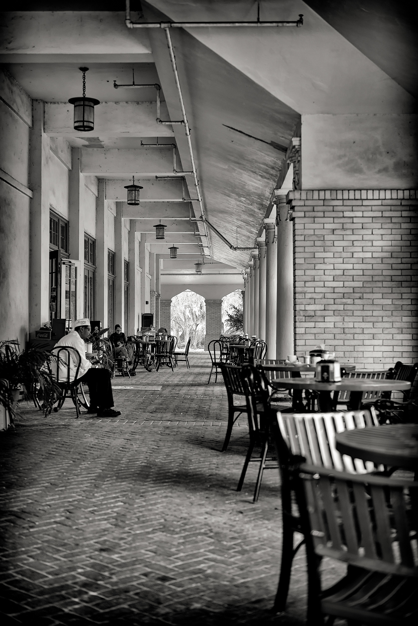 This is the arcade of the Casino Building in City Park, built in 1913 as a refreshment pavilion — which is a nicer way of saying it never actually had gambling in it, whatever the name promises. For six years, starting in 2012, this corner of it belonged to Morning Call, the 1870s coffee-and-beignet stand that got run out of the French Market by rising rent and came here looking for calmer water. It didn't find it. In 2018 the city put the lease up for bid and Café du Monde, its old French Market rival, won it outright, and Morning Call was gone by January 2019. The oaks through the archway back there don't know any of this happened and don't care.