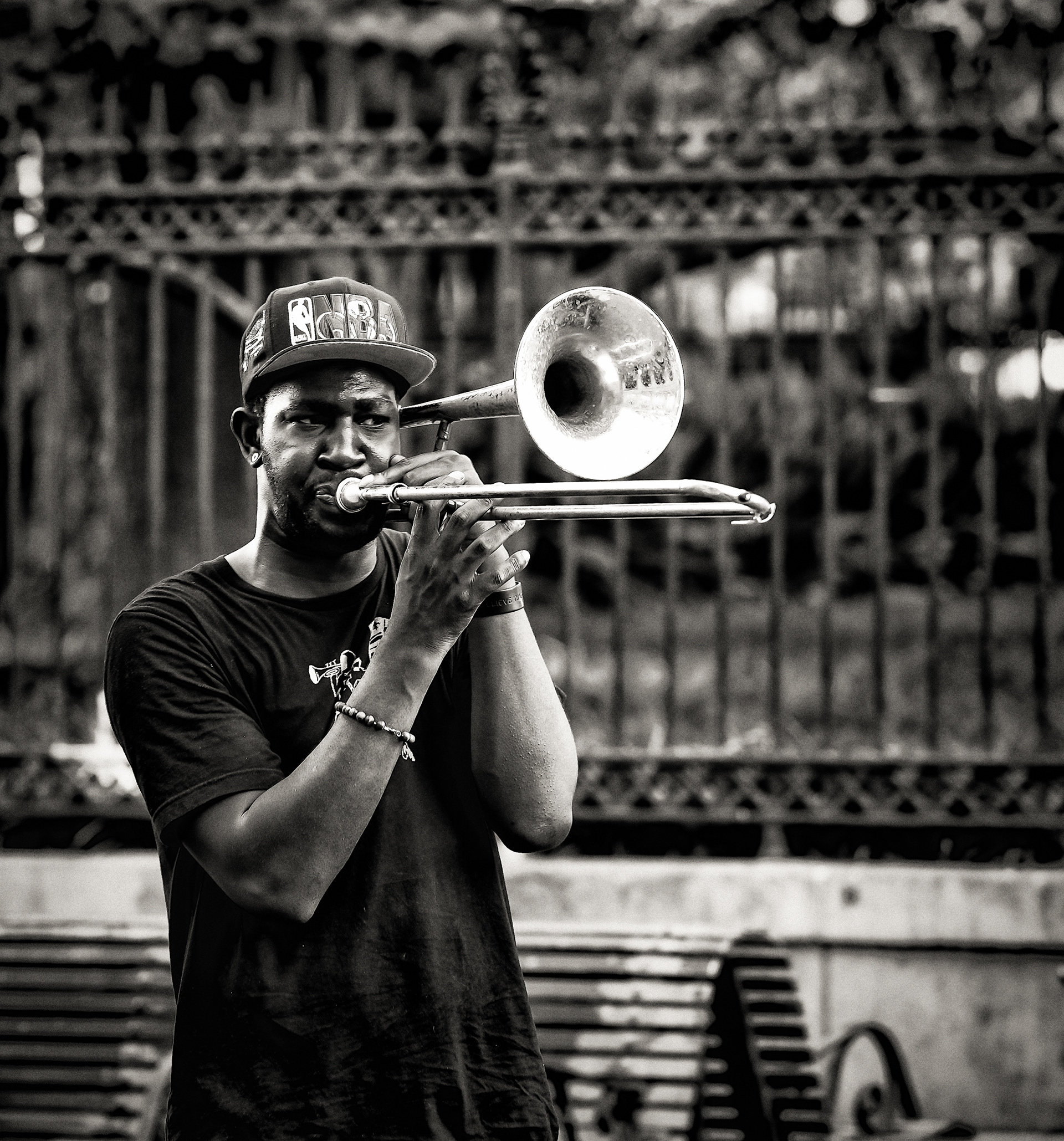 No band this time — just him, a trombone, and an iron fence. Working New Orleans brass players mostly come up this way: busking alone on Quarter sidewalks, a stop between the school band program and a booked gig. He's not settling for a street corner. This is how you get good enough to leave it.