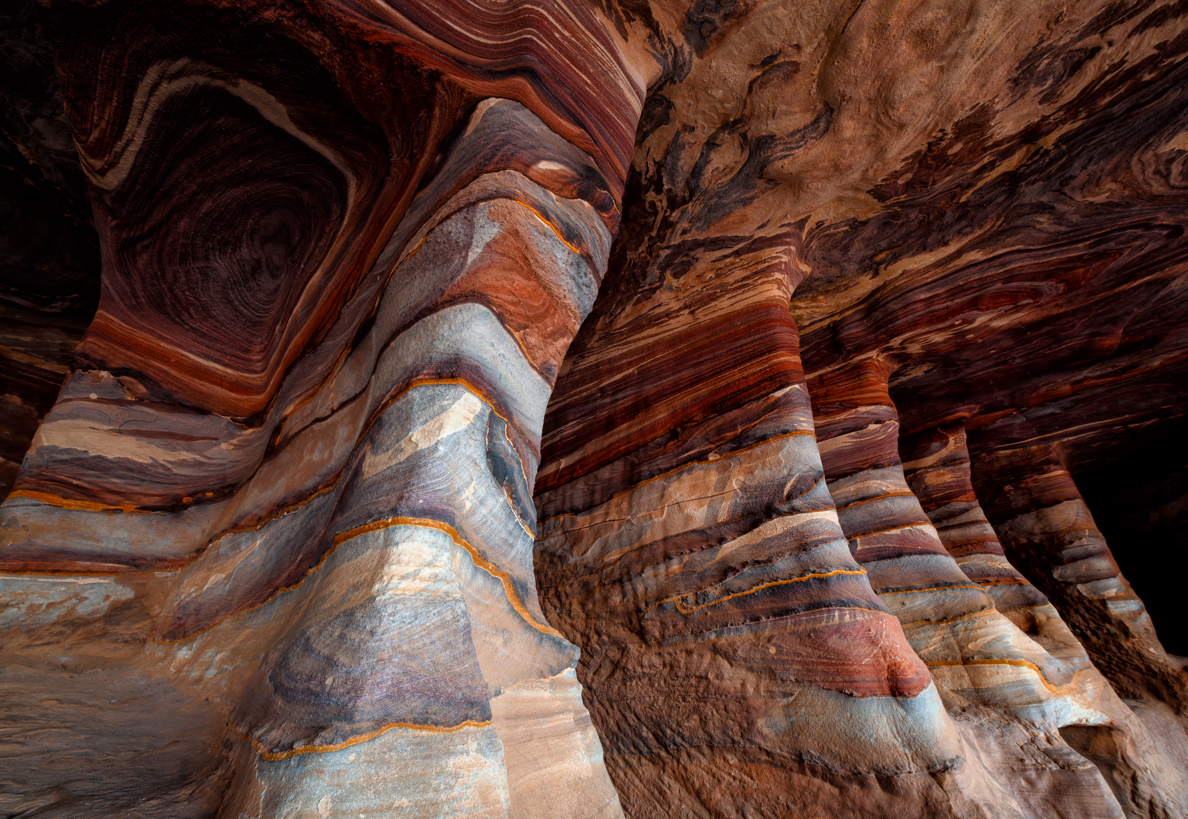 Inside one of Petra's Royal Tombs — the sandstone swirls in natural mineral bands, some of the most striking color in the whole necropolis.