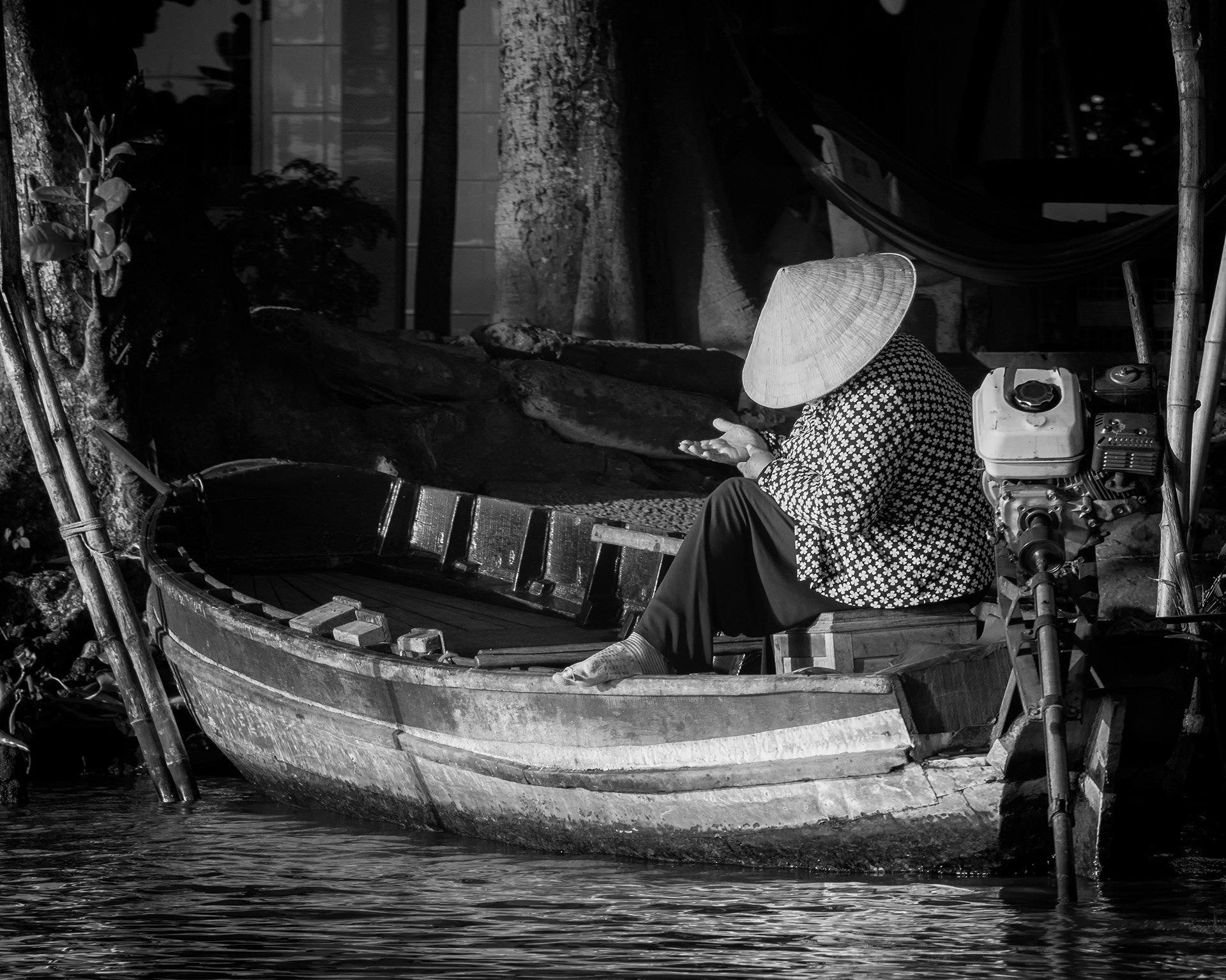 Mekong Delta. A woman sits in her boat, studying her own open hand — a splinter, maybe, or a blister, I couldn't tell. Her toes had worked their way out through her socks, which struck me as funny in its own small way. Not the reason behind it. Just the toes.