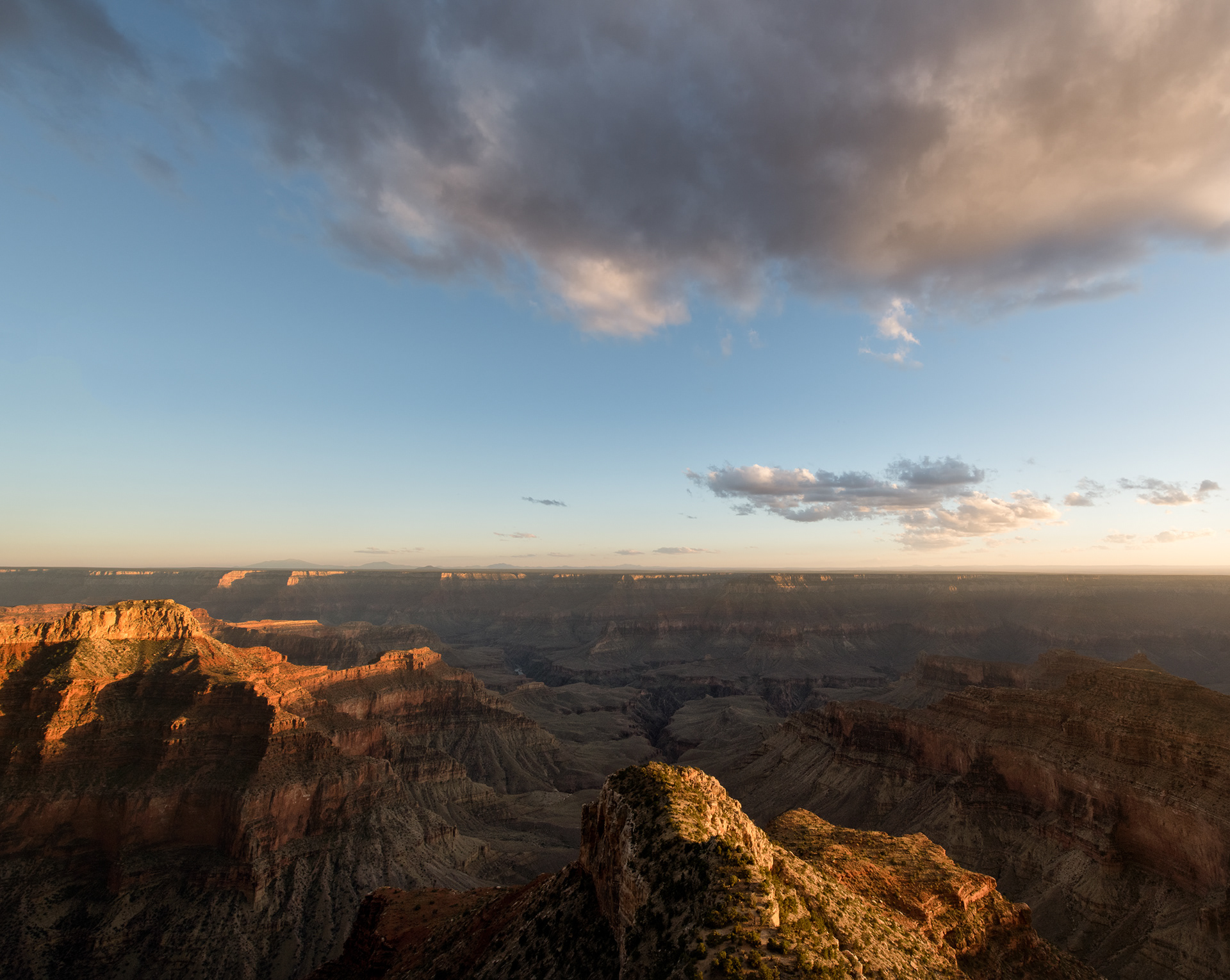 Grand Canyon, storm cell moving through. The canyon's own vertical relief — a full mile from rim to river — means weather changes with elevation almost like a trip north to south: pine forest and cool air up top, cactus and near-desert heat at the bottom, sometimes a twenty-degree spread between them on the same afternoon. That's also why rain up here doesn't always mean rain down there — a storm can dump hard on the rim and never reach the floor at all, drying out mid-fall into virga before it clears the canyon walls. Arizona's summer monsoon, roughly July through September, is what reliably builds cells like this one; the rest of the year the sky mostly just watches.