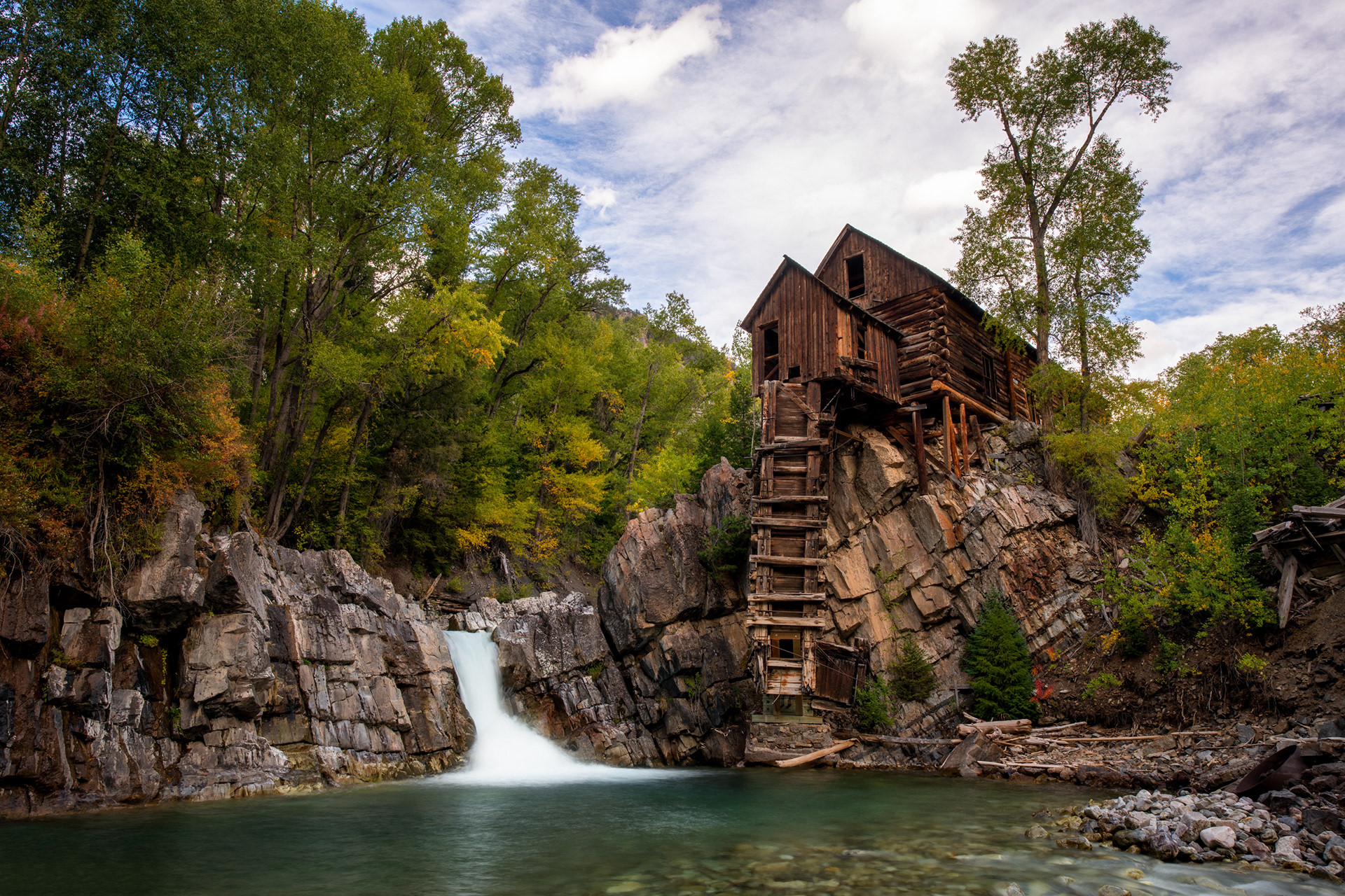 Crystal Mill, on the Crystal River near the ghost town of Crystal — and despite the name, it never actually milled anything. Built in 1893 for the Sheep Mountain Tunnel and Mining Company, it was really a compressor station: a horizontal waterwheel spun by the river drove an air compressor, and the compressed air ran pneumatic drills in the silver mines up the hill, piped in rather than any ore ever passing through the building itself. It worked for about twenty-four years, until the mine closed in 1917, and it's been sitting on this same outcrop, unpowered, ever since — reachable now only by the same rough four-wheel-drive road that got equipment in here in the first place.