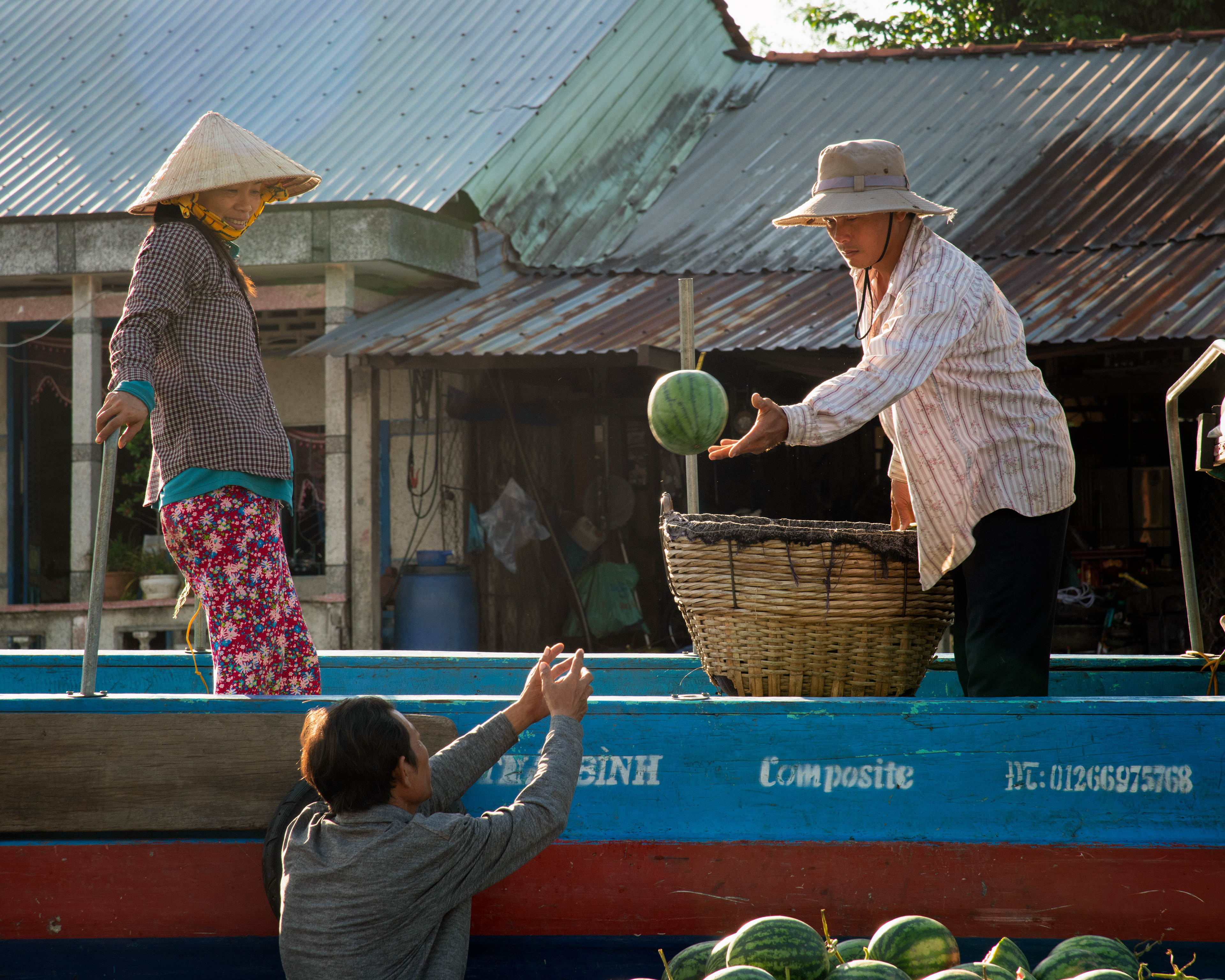 Cai Rang floating market. Two men toss watermelons hand to hand, boat to boat, faster than they look like they should. A woman looked on, smiling the whole time.