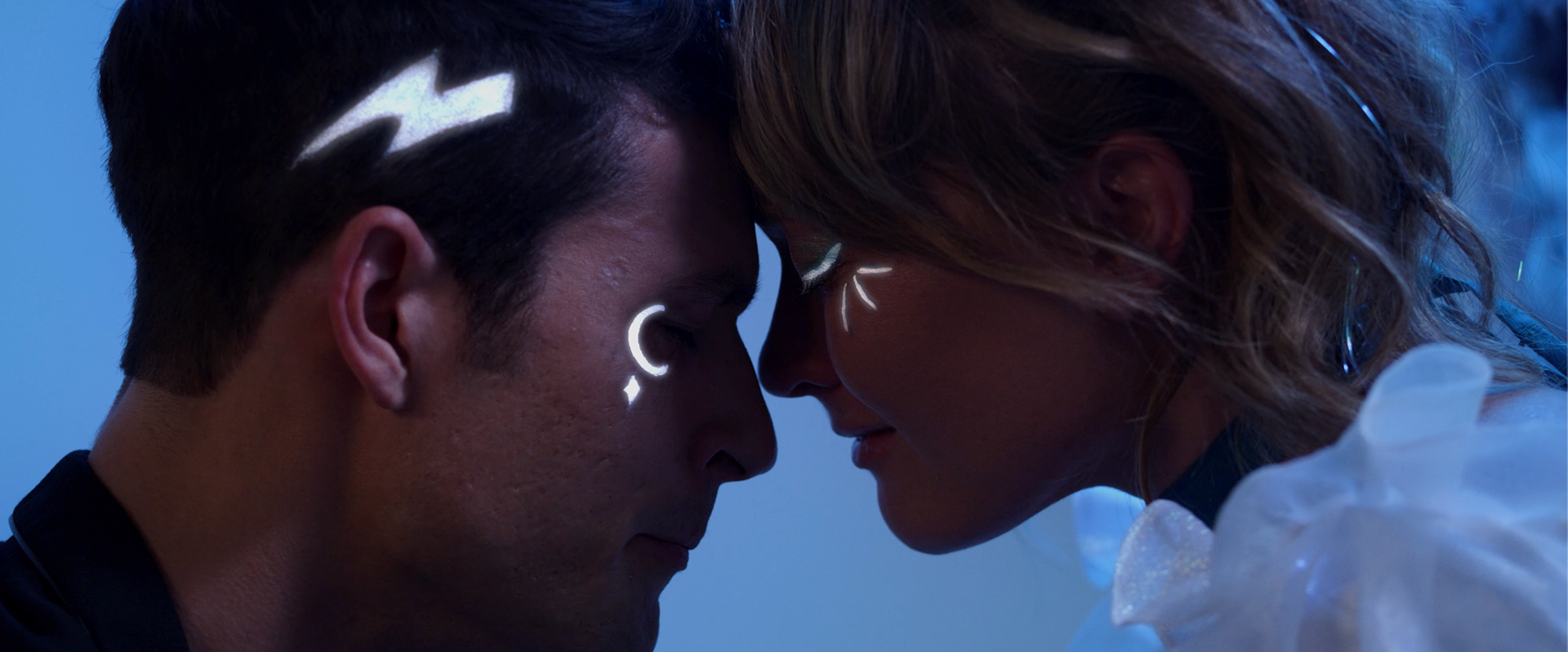 The images on their faces light up when their foreheads touch suggesting they are perhaps otherworldly, not fully human.