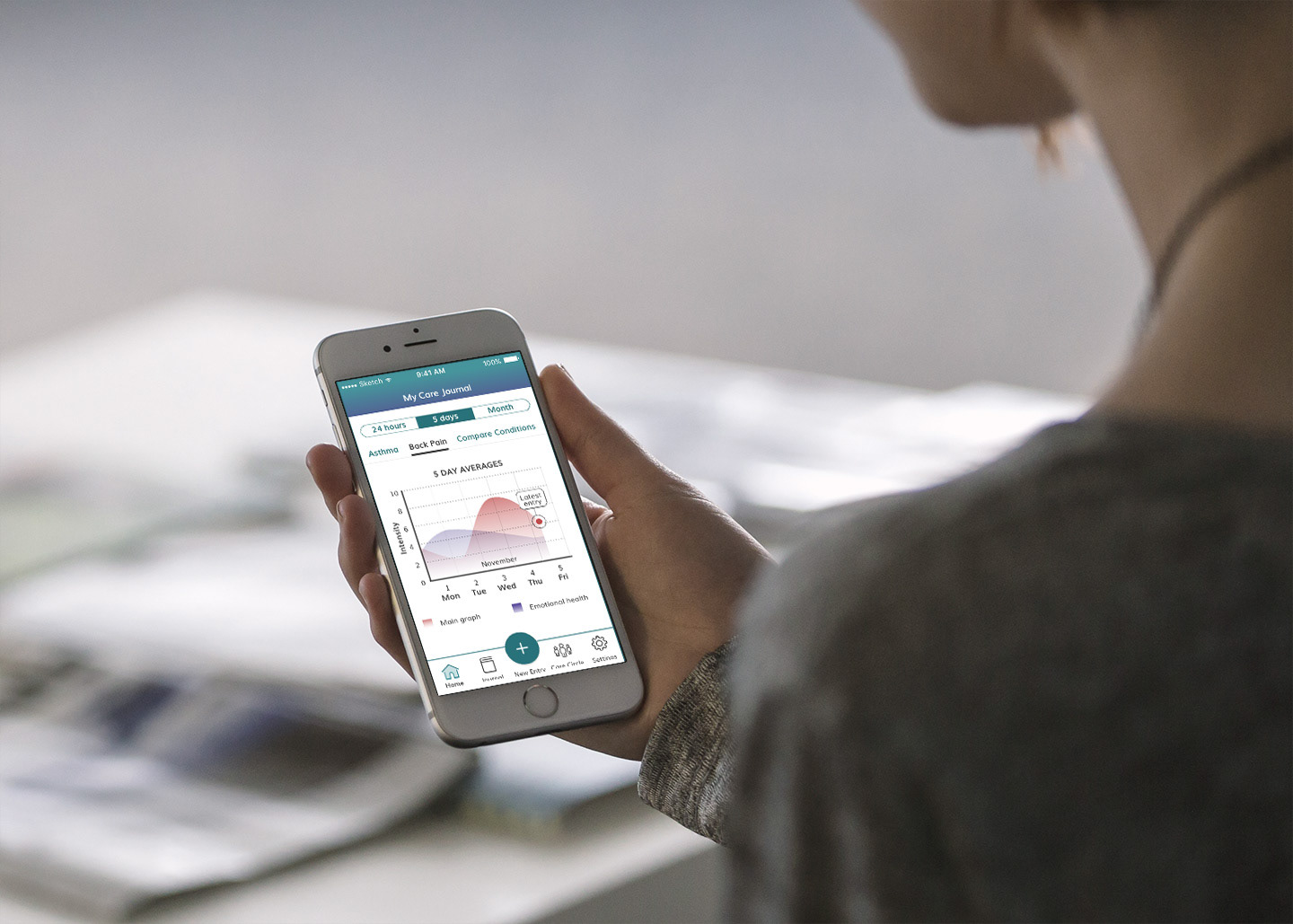 Image of a woman holding a prototype of my app concept, Care Journal.