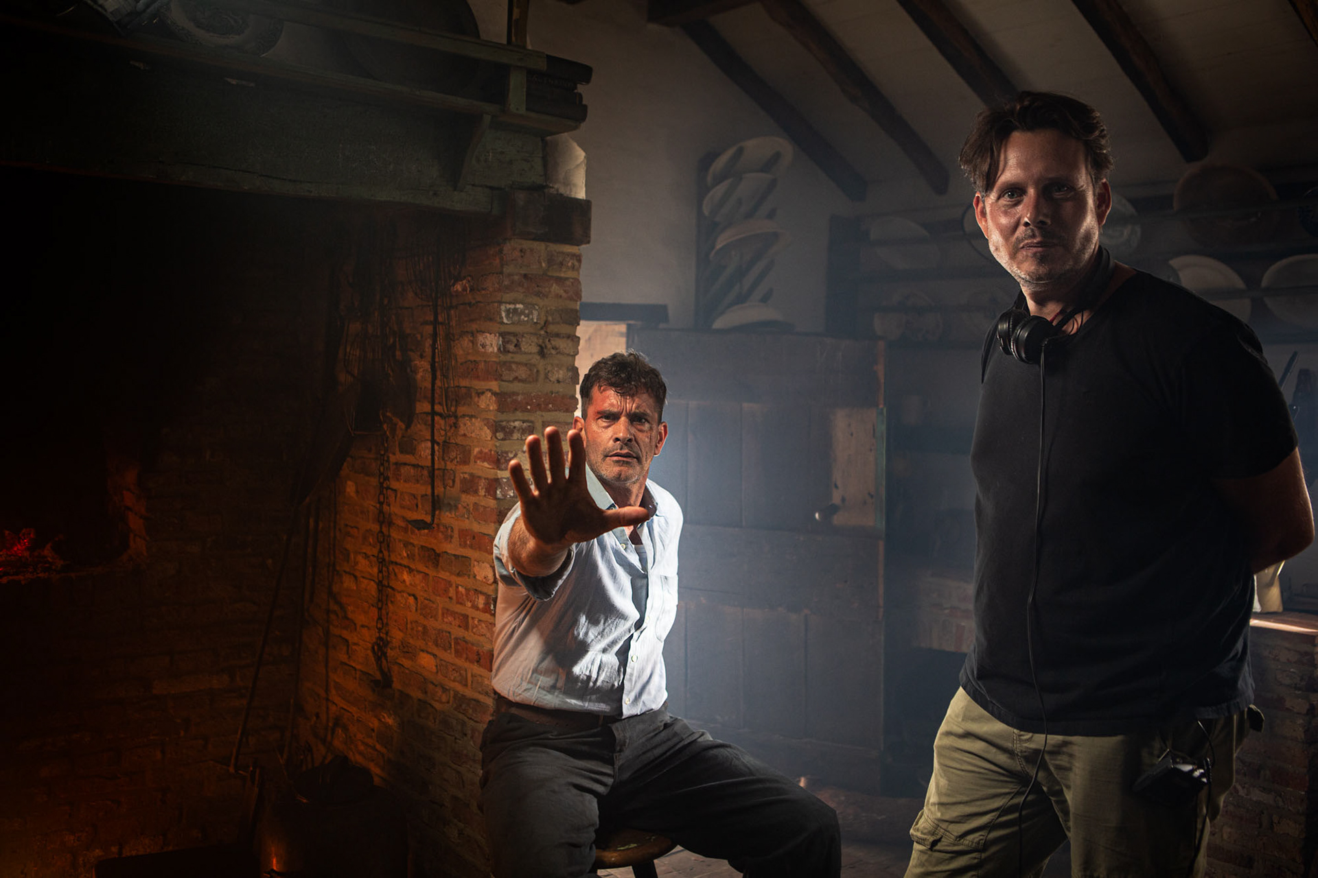 Koen De Bouw playfully signaling stop at camera and director Sven Huybrechts looking into the camera.