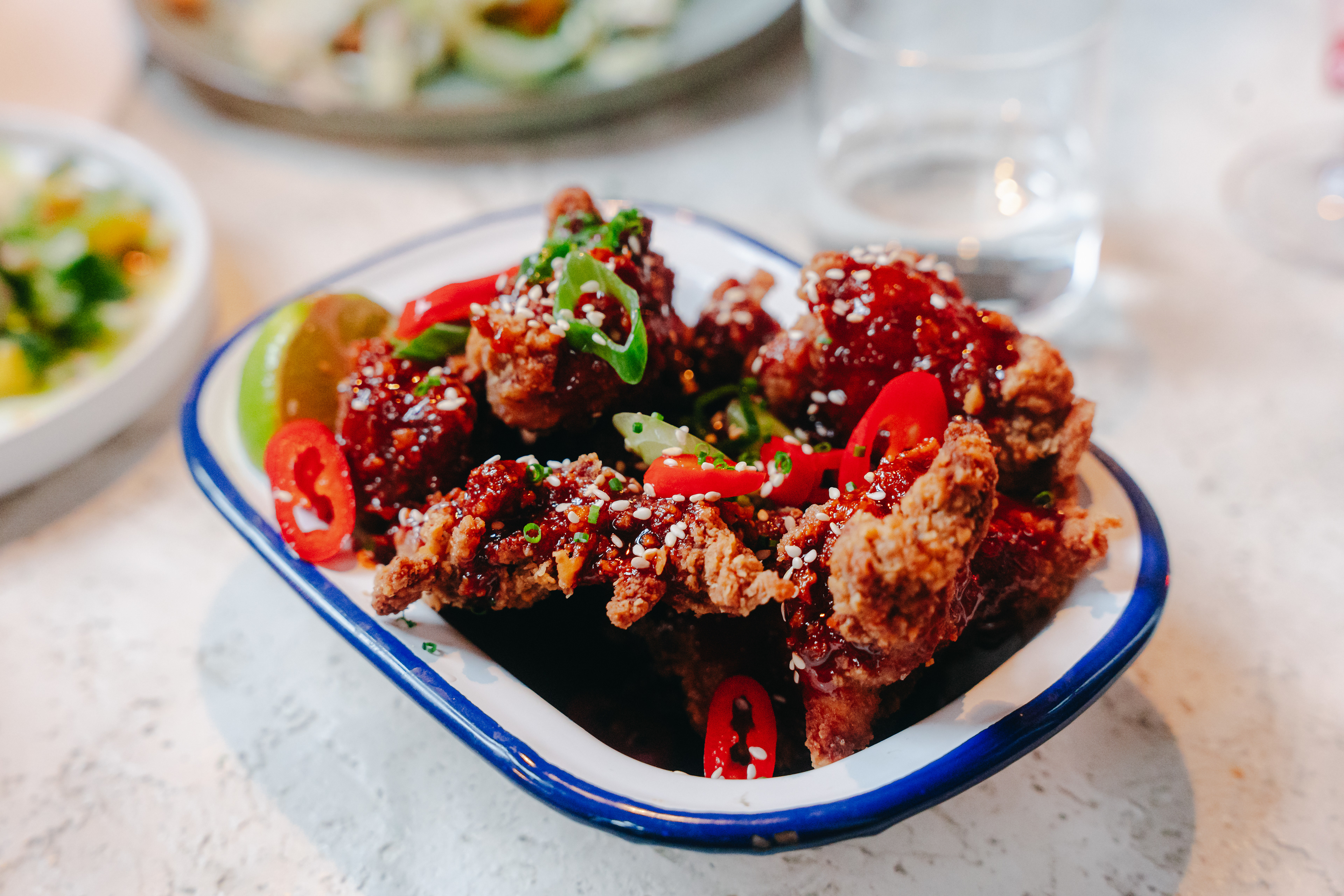 Krokante kip met chilisaus en sesam, smakelijk en gedetailleerd in beeld gebracht voor een menukaart.