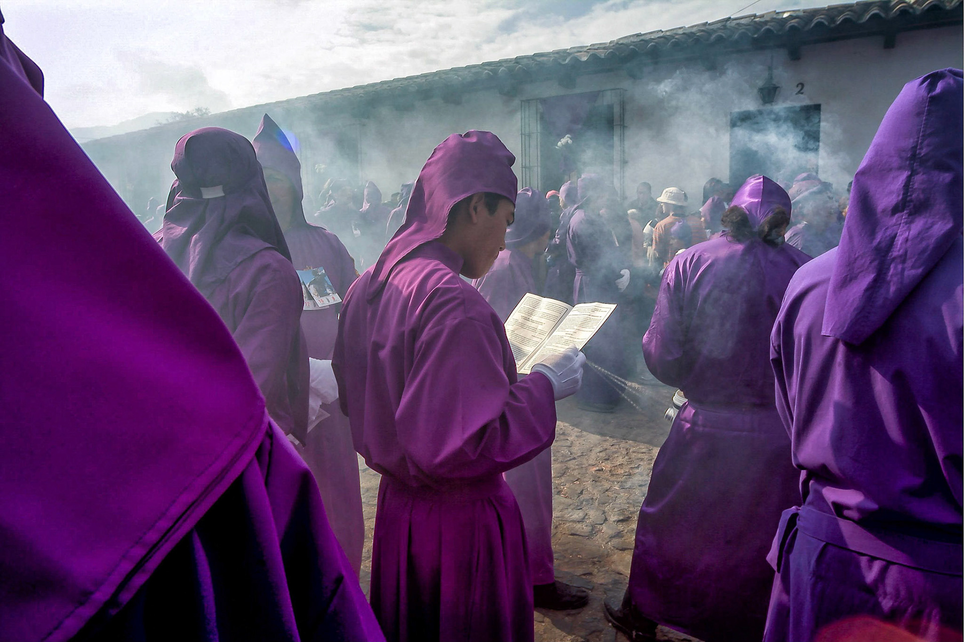 A Pallbearer dressed in purple robes reads from  a book of prayers before carrying  the procession of San Bartolo in Antigua Guatemala, 20 miles west Guatemala city,28th March 2004.  Guatemalans celebrate processions that re-enact the martyrdom of Jesus before his crucifixion. San Bartolo is the largest procession in  the historical city of Antigua Guatemala, the image of Jesus carried by 90 pallbearers dates from 1640, (Photo/Carlos Lopez-Barillas)