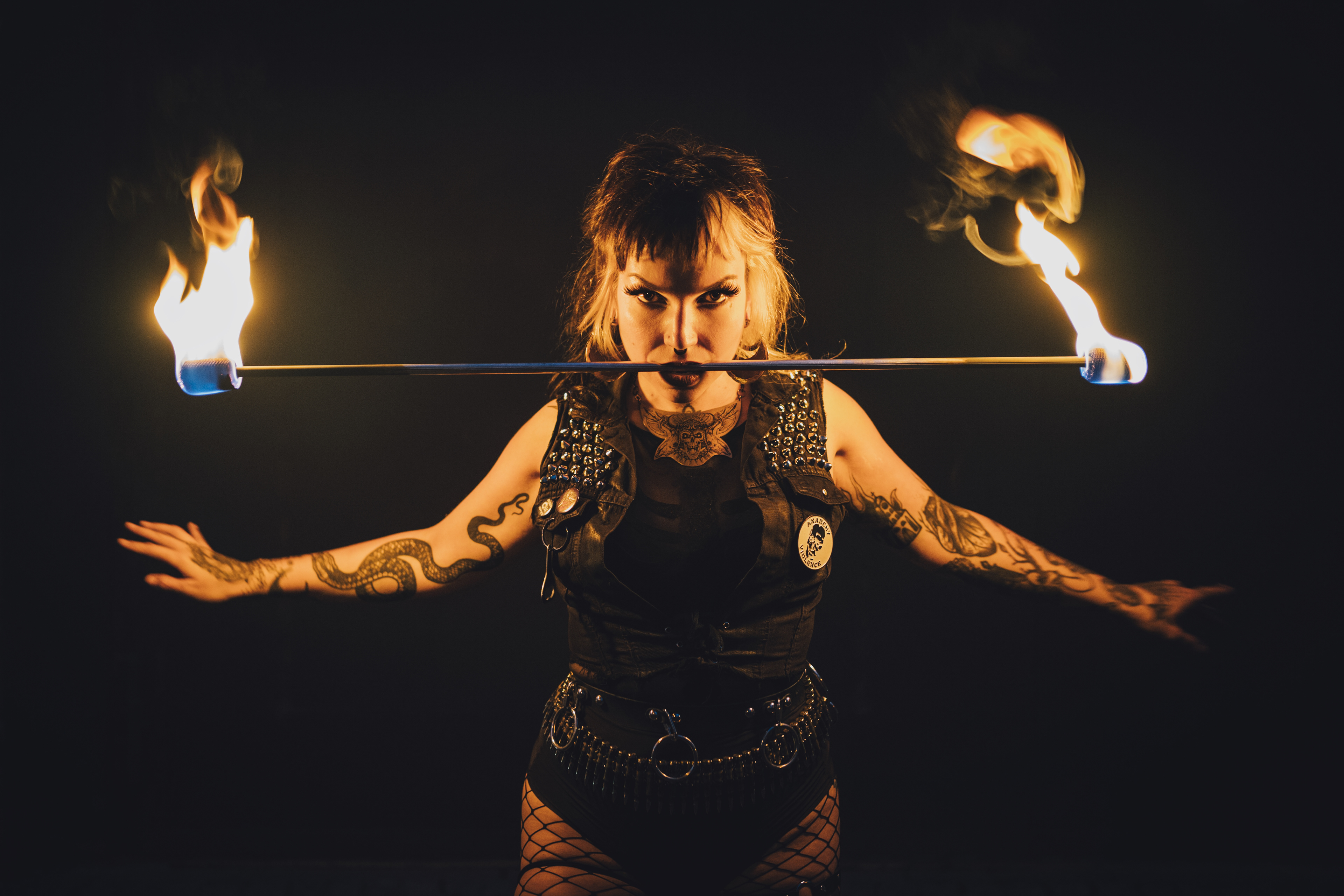 Performer of electric sideshow Evilyn Frantic captured during her fire show performance biting on a fire stick