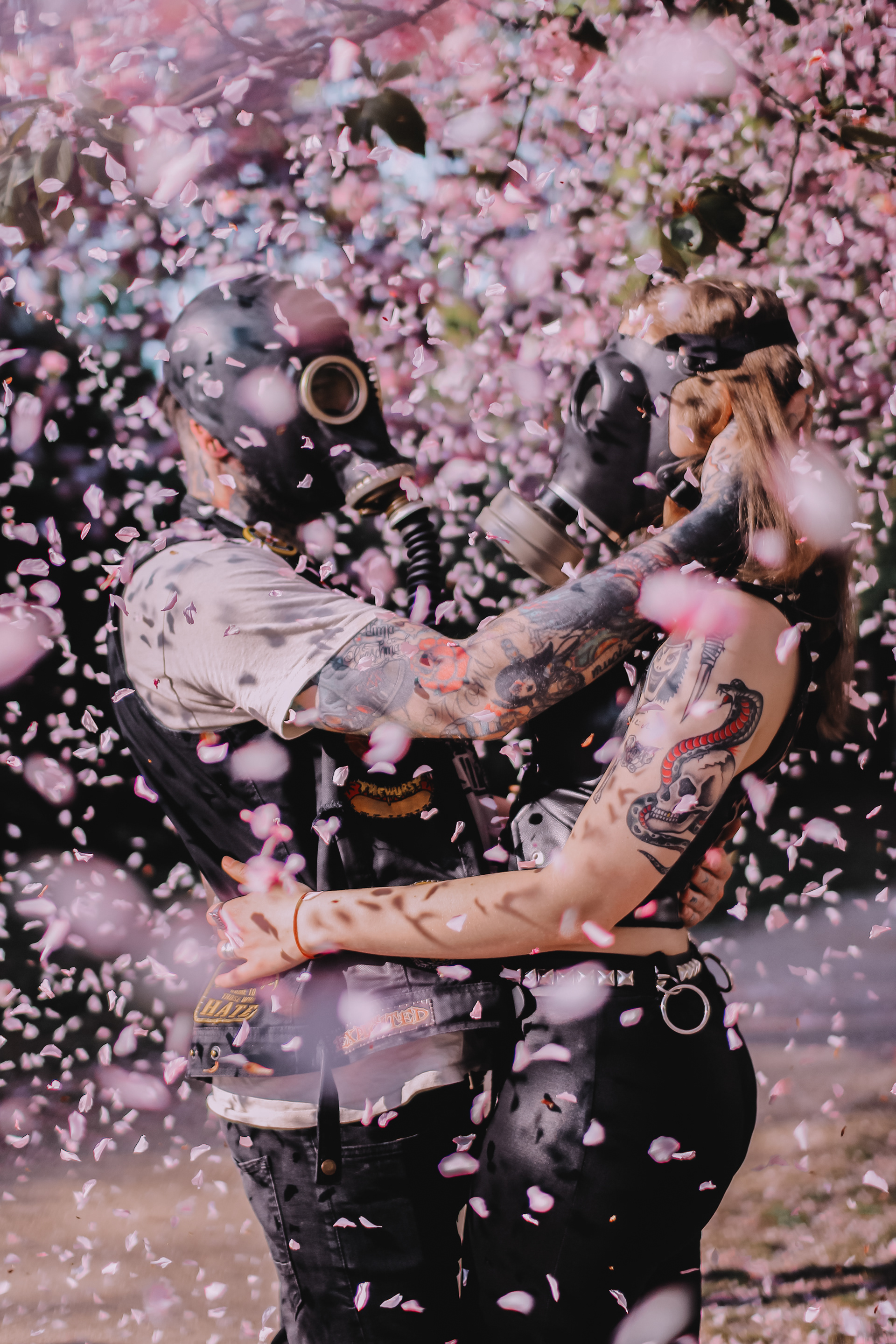 Pandemic Love Affair covid post apocalyptic series shot of a couple in love wearing gas masks under a cherry blossom tree