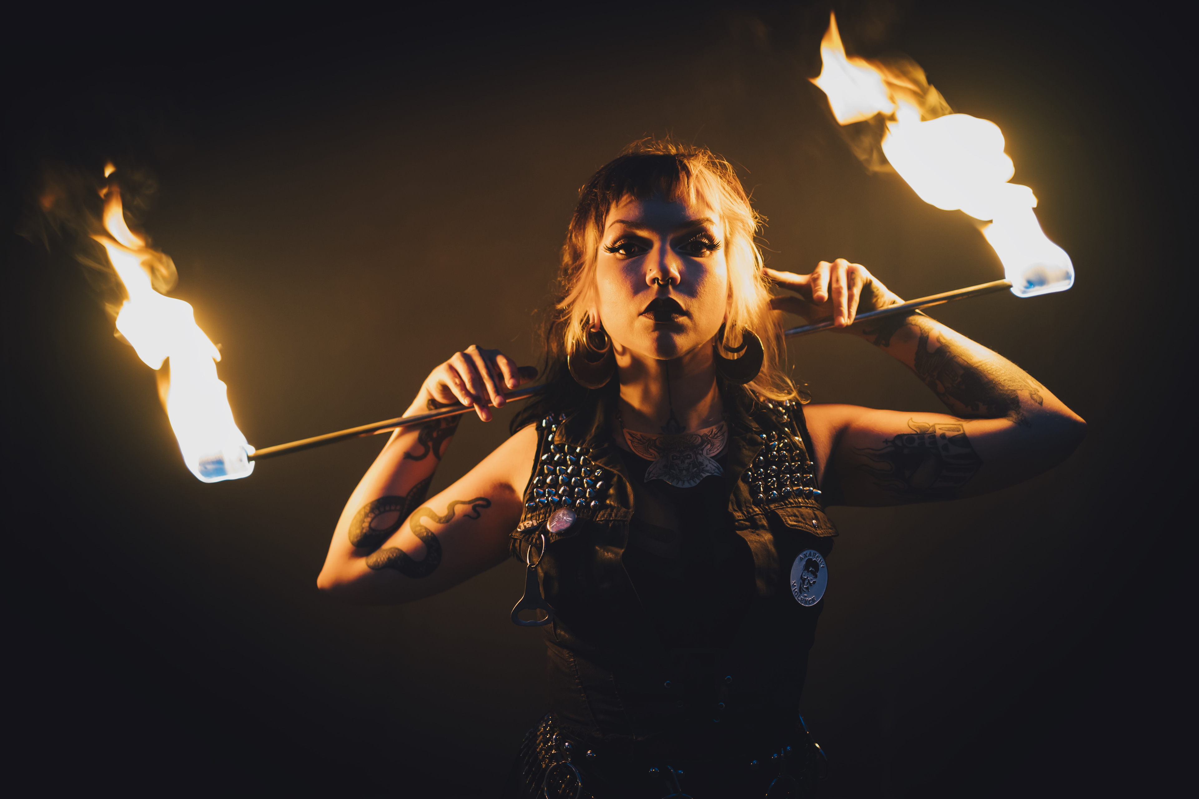 Performer of electric sideshow Evilyn Frantic captured during her fire show holding a fire stick behind her back