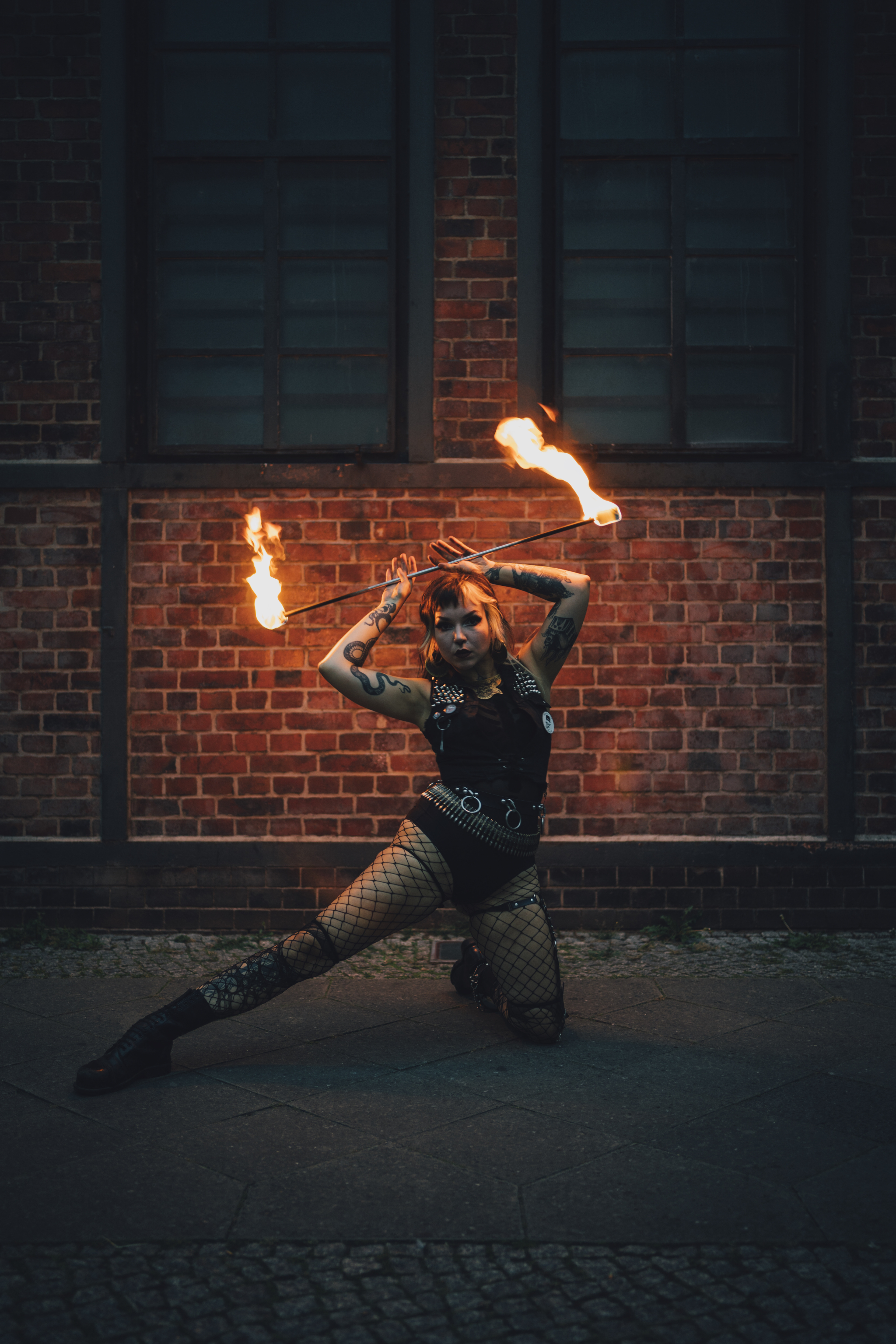 Performer of electric sideshow Evilyn Frantic captured during her fire show holding a fire stick above her head in Berlin