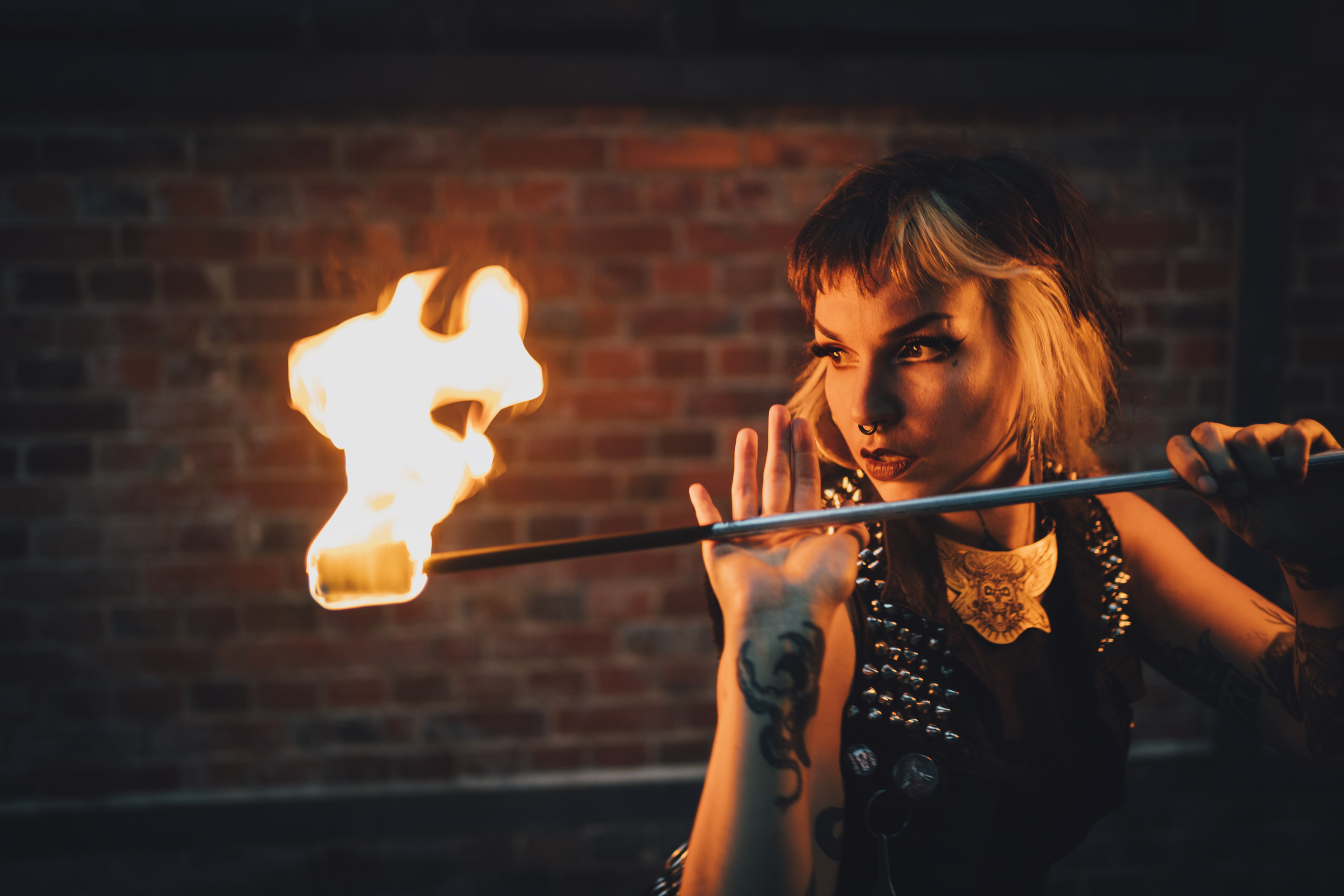 Performer of electric sideshow Evilyn Frantic captured during her fire show looking into the fire with desire in her eyes