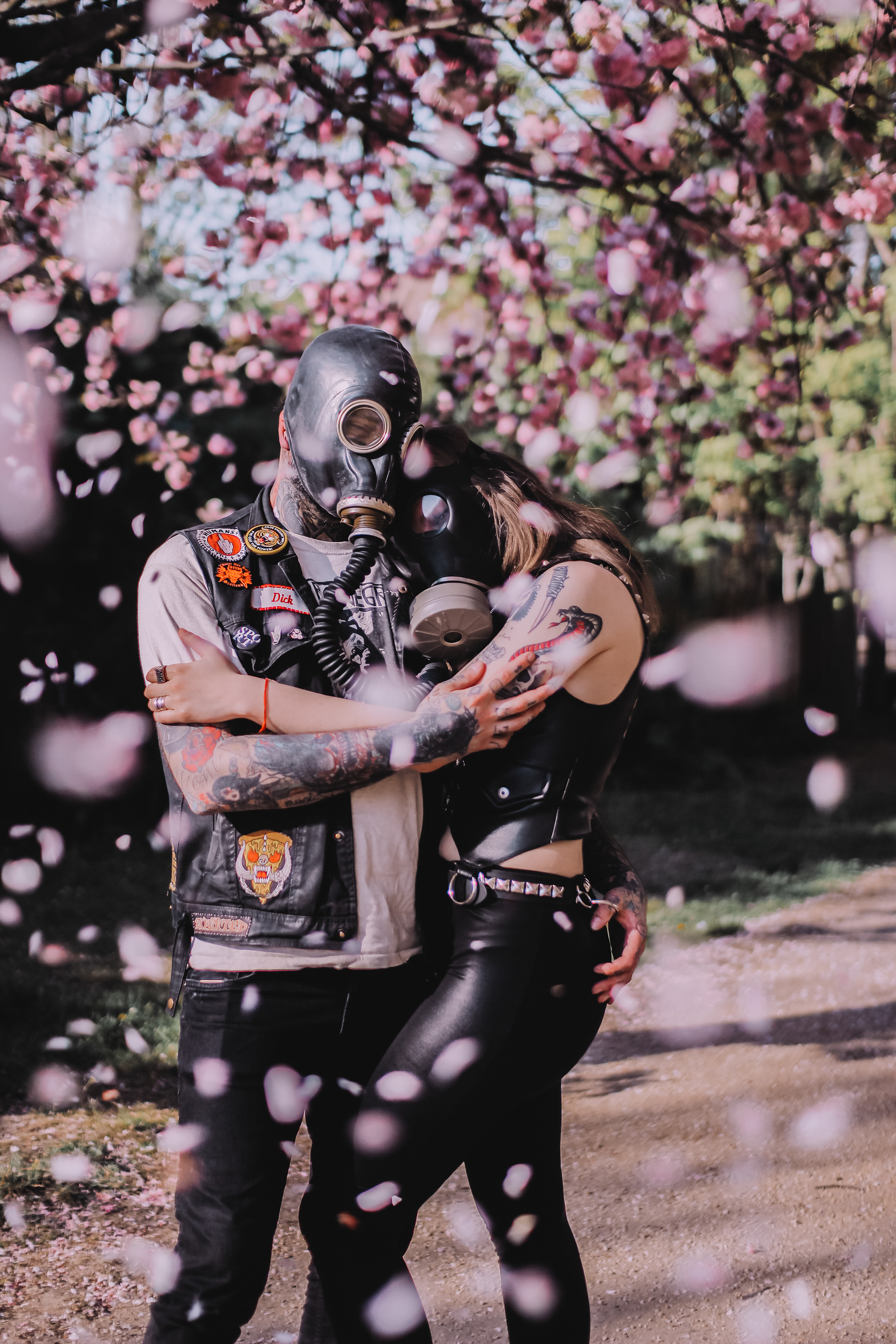 Pandemic Love Affair covid post apocalyptic series shot of a hugging couple wearing gas masks under a cherry blossom tree