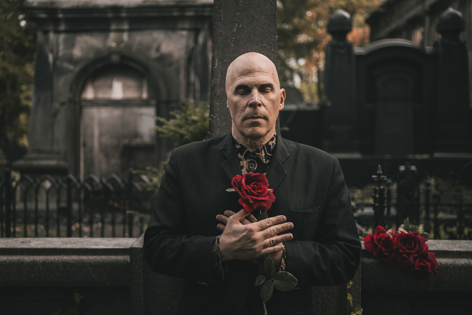 Nikolas Schreck american sinager of death rock band Radio Werewolf holding red rose with eyes closed the cemetery in Berlin