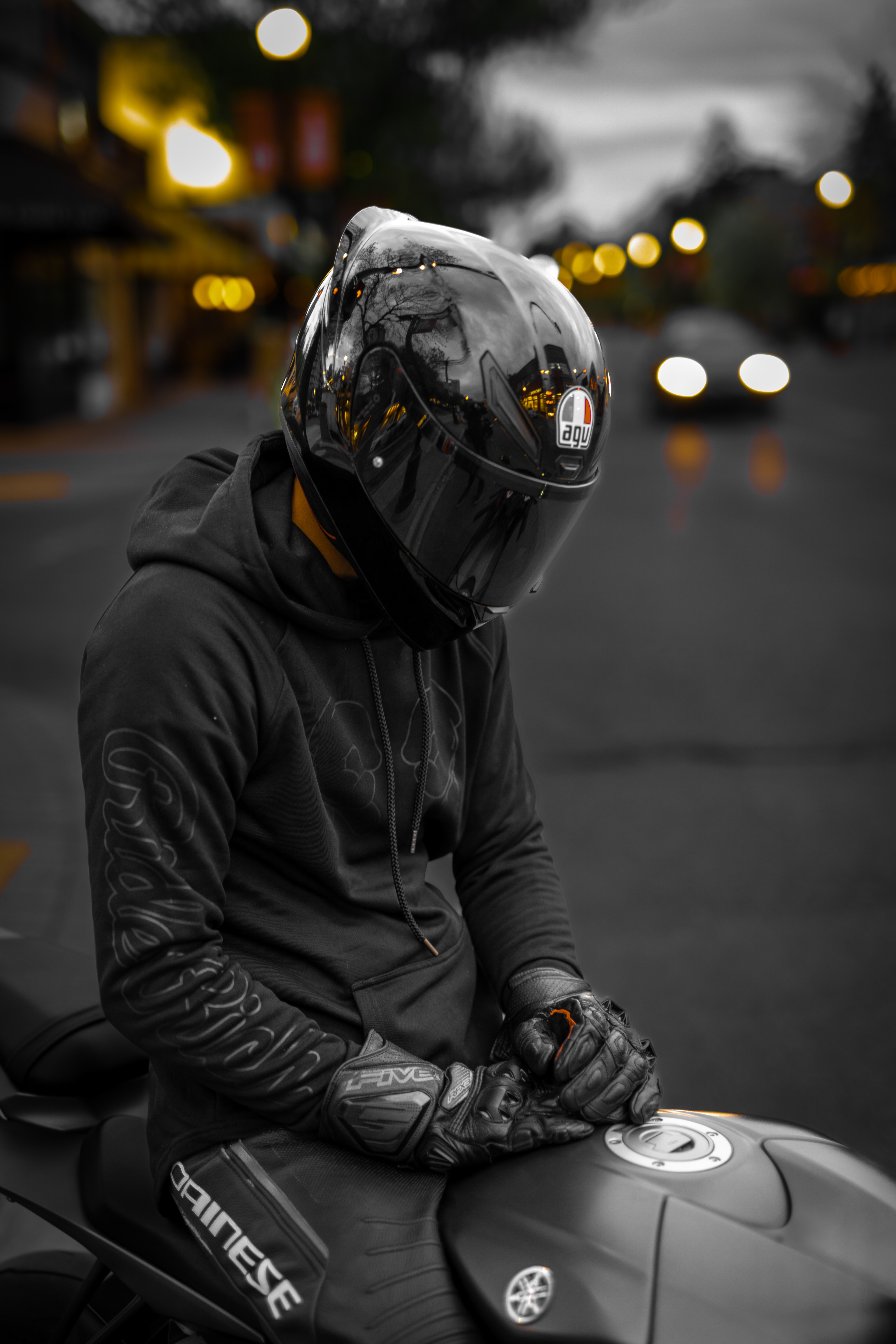 Motorcycle rider wearing AGV helmet and Dainese gear sitting on a Yamaha sportbike in downtown Calgary, with blurred evening lights in the background.