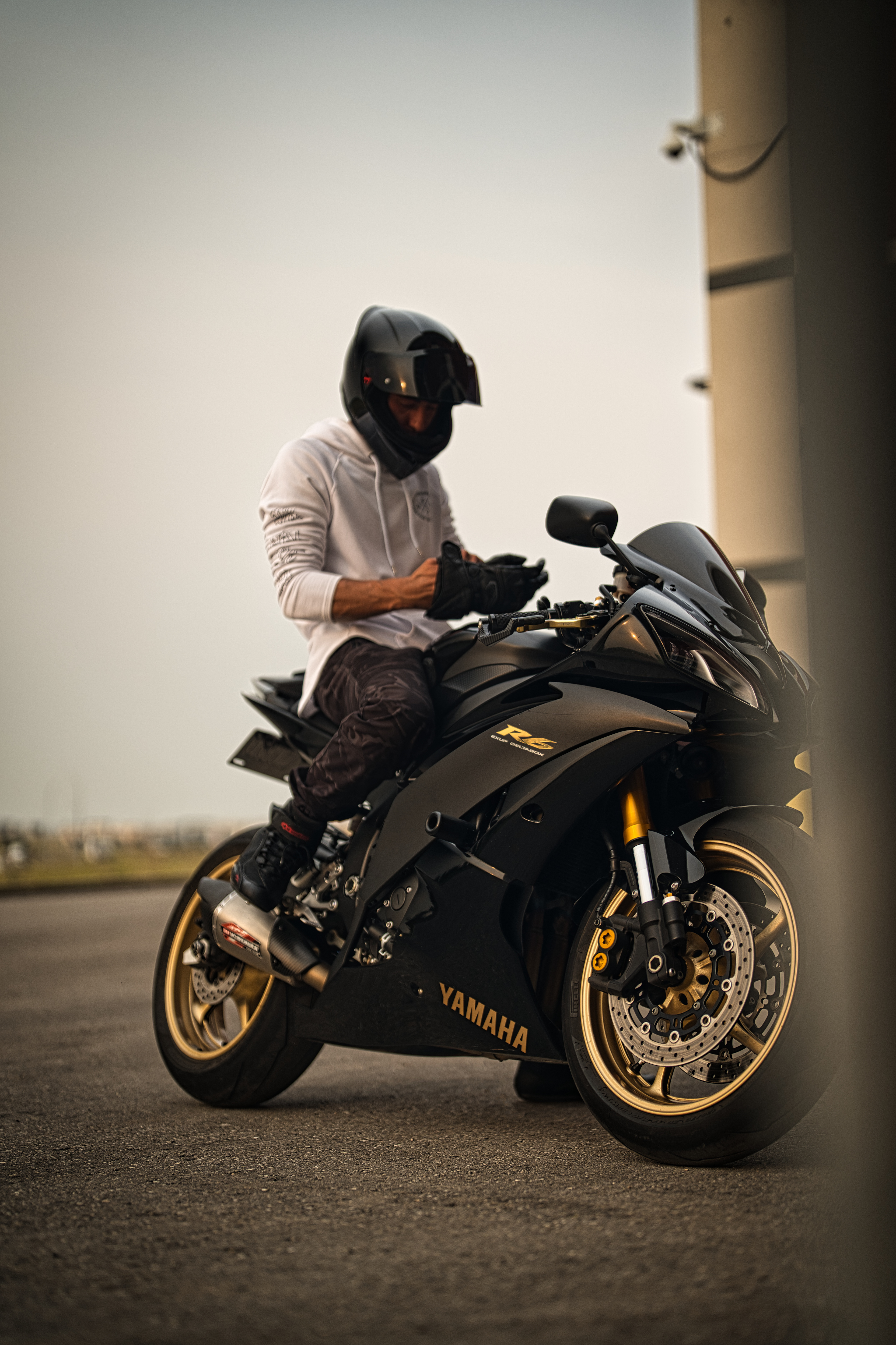 Yamaha R6 motorcycle photoshoot in Calgary by Black Rev Studio—rider wearing a white hoodie and full-face helmet preparing to ride at golden hour.