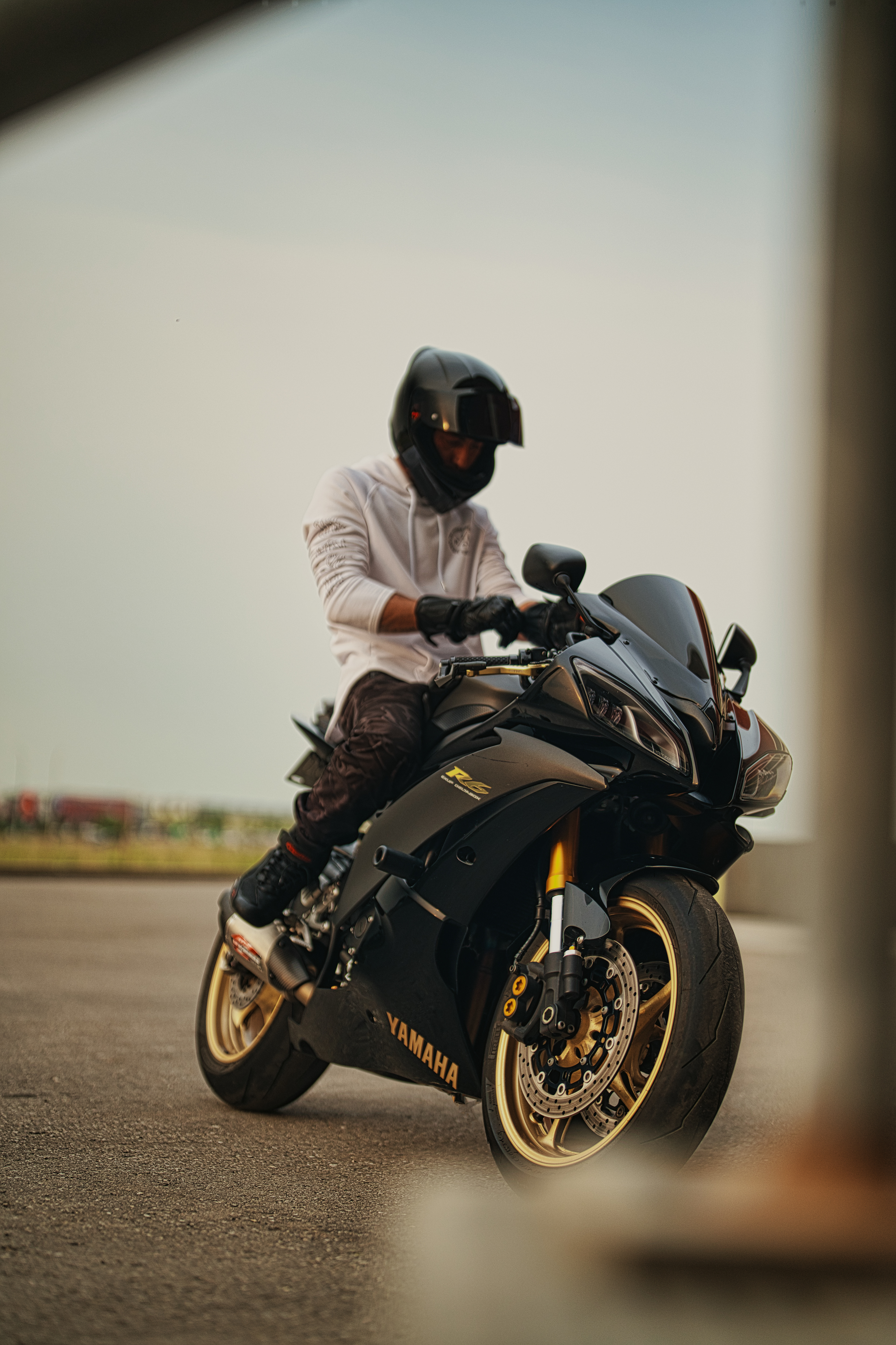 Yamaha R6 motorcycle photoshoot in Calgary by Black Rev Studio—rider wearing a white hoodie and full-face helmet preparing to ride at golden hour.