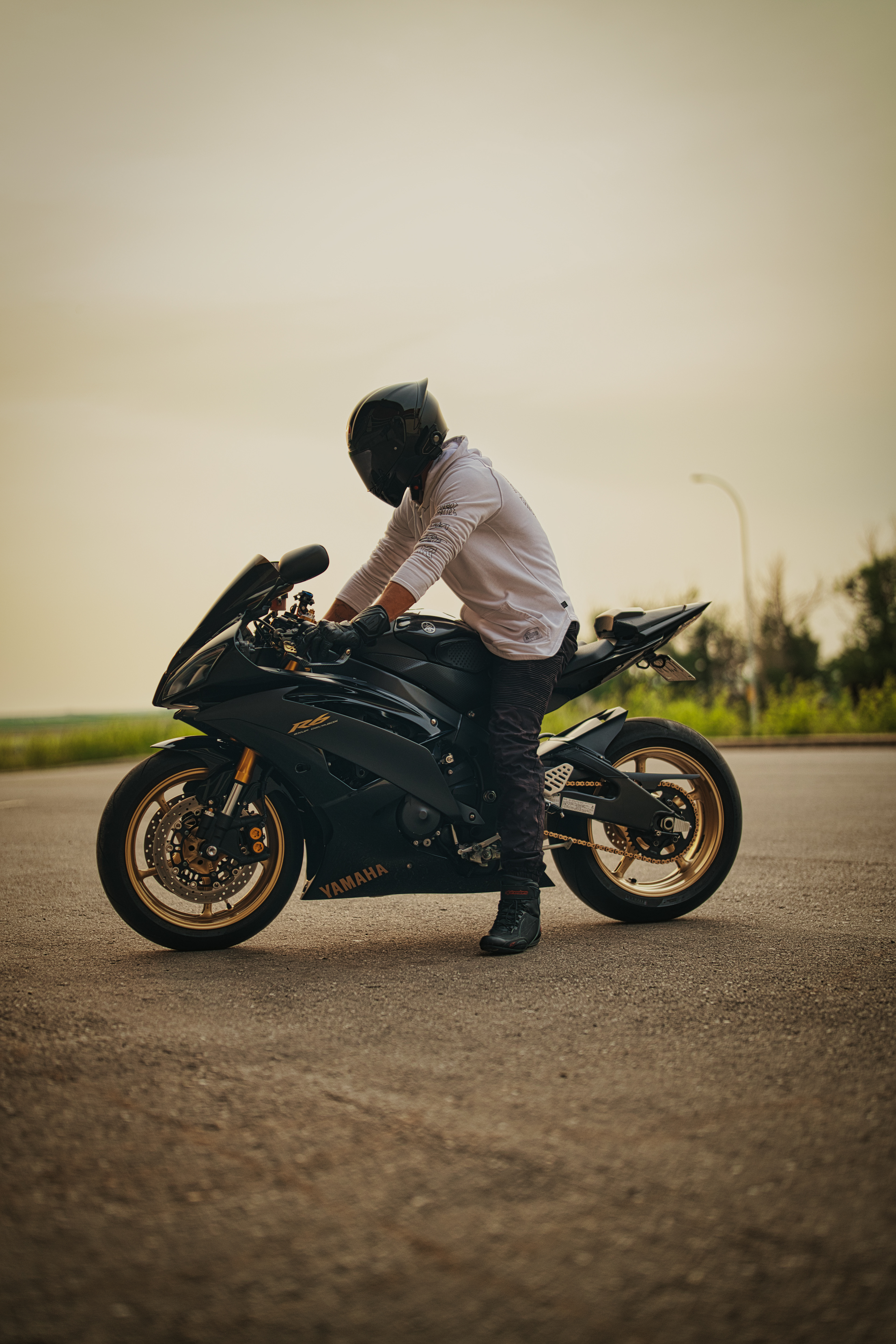 Golden hour motorcycle photography in Calgary by Black Rev Studio—rider in white hoodie with full-face helmet straddling a matte black Yamaha R6 sportbike.