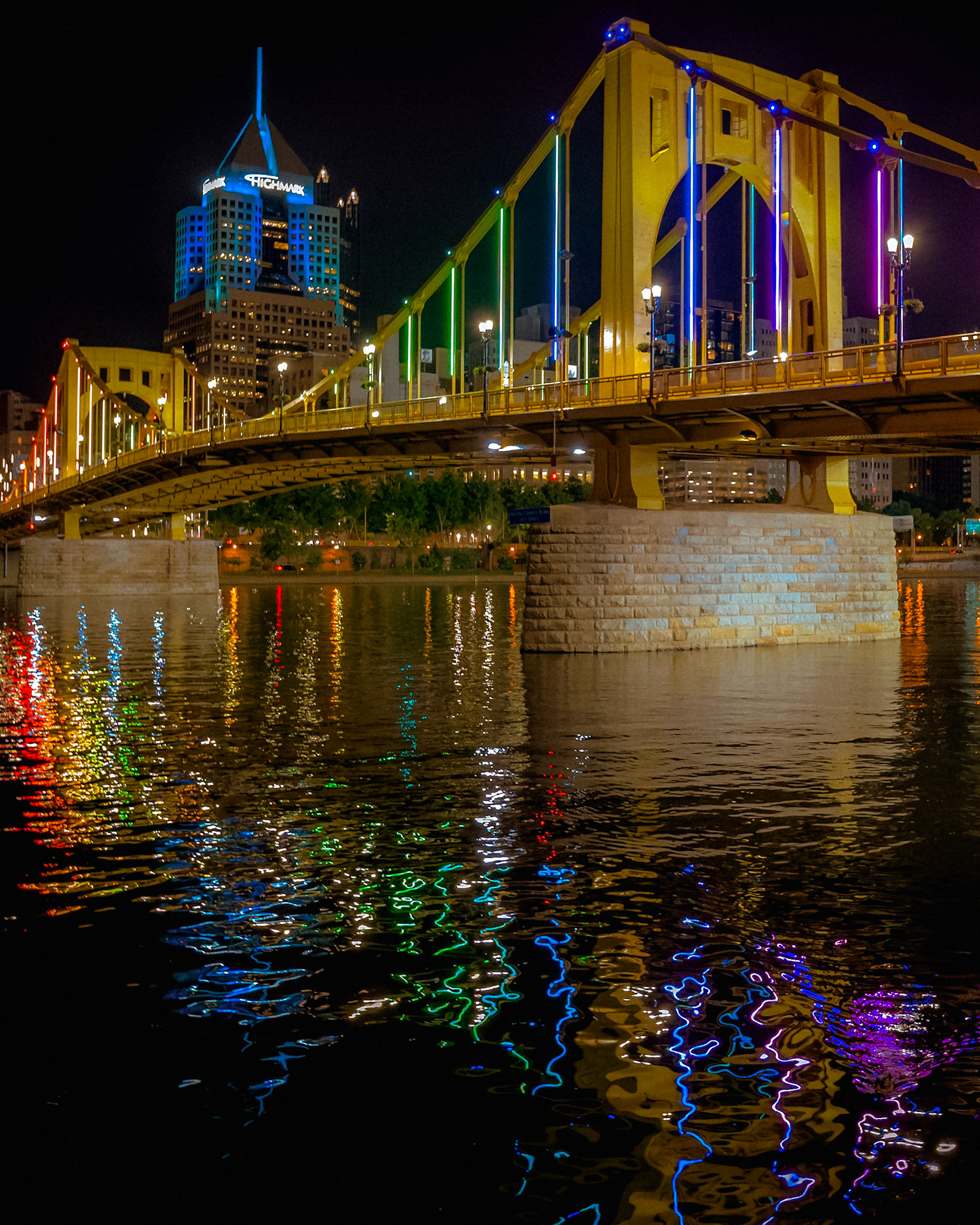 A bridge of light and color stretches across the river, its reflection rippling like a gateway between realms. In Norse myth, Bifröst was the bridge to the gods—here, the glow of Pittsburgh’s night turns steel and stone into something just as ethereal.