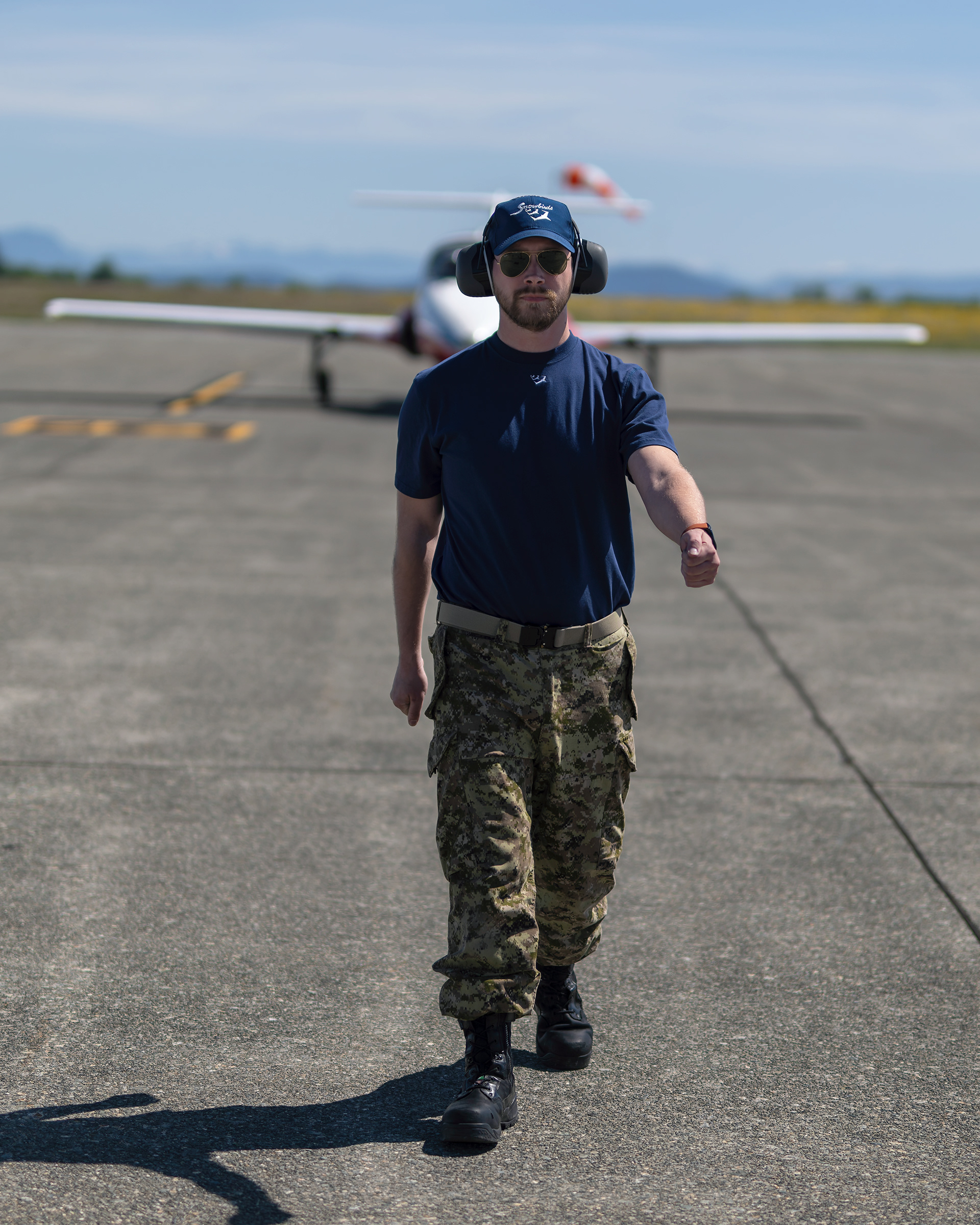 A Canadian Forces Snowbirds technician walks the flight line after completing pre-flight inspections on a CT-114 Tutor during spring training at CFB Comox. Fine art aviation documentary photography by Kevin Prentice.