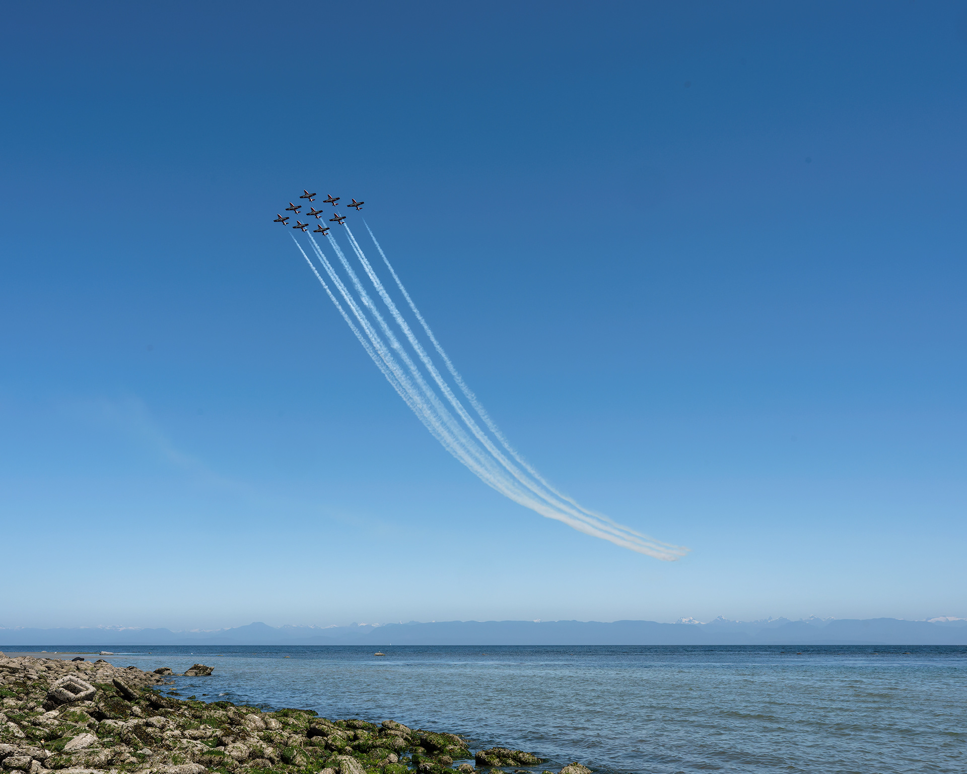 The Canadian Forces Snowbirds (431 Air Demonstration Squadron) perform a precision formation flight, leaving signature white smoke trails against a clear sky during their 2026 spring training demonstration over Vancouver Island. Fine art aviation photography by Kevin Prentice.