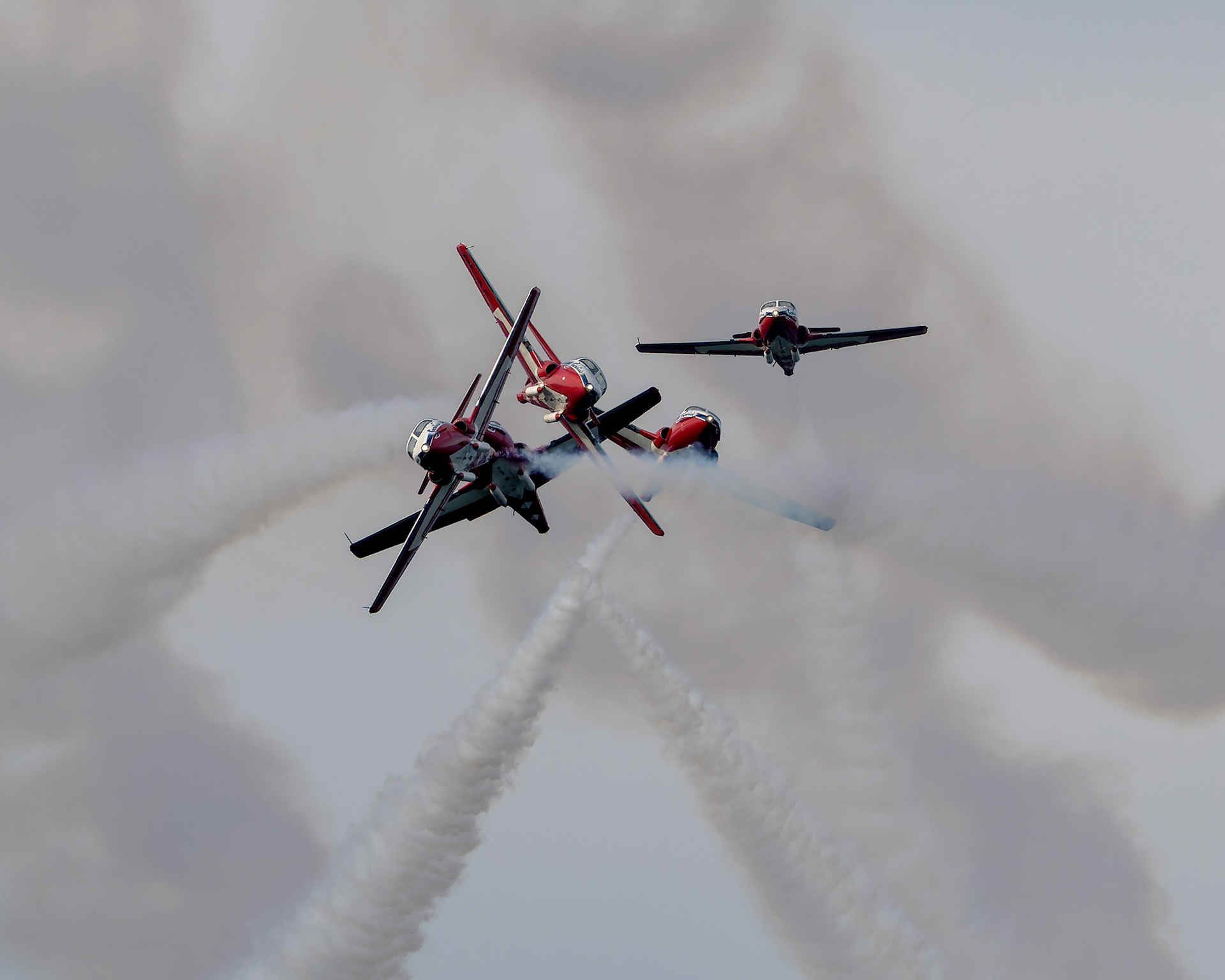 Canadian Forces Snowbirds CT-114 Tutor jets performing a dynamic precision aerobatic crossover maneuver with smoke trails. Aviation photography by Kevin Prentice.