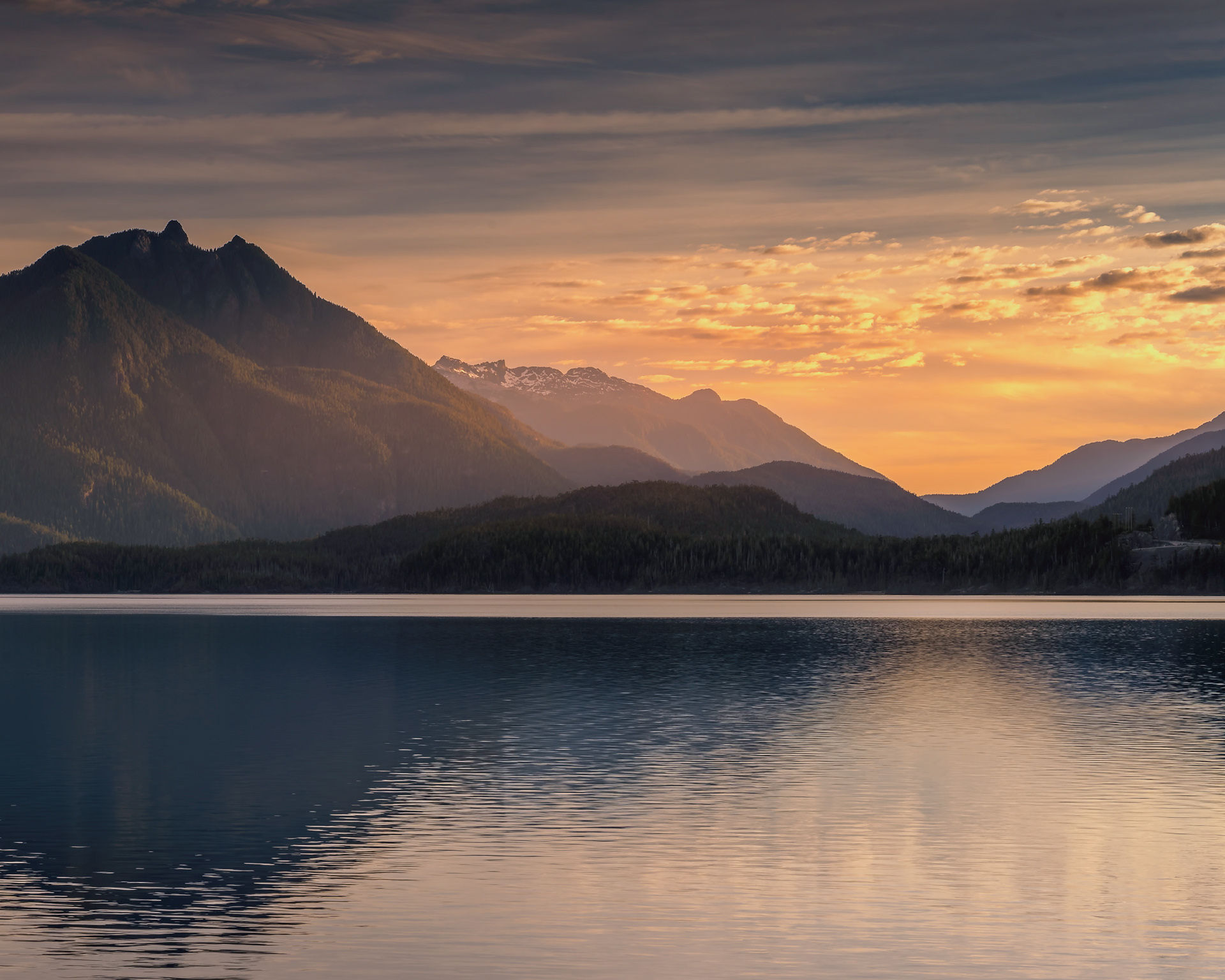 First light of sunrise glowing behind the mountain ranges bordering Kennedy Lake on Vancouver Island, British Columbia. Fine art landscape photography by Kevin Prentice.